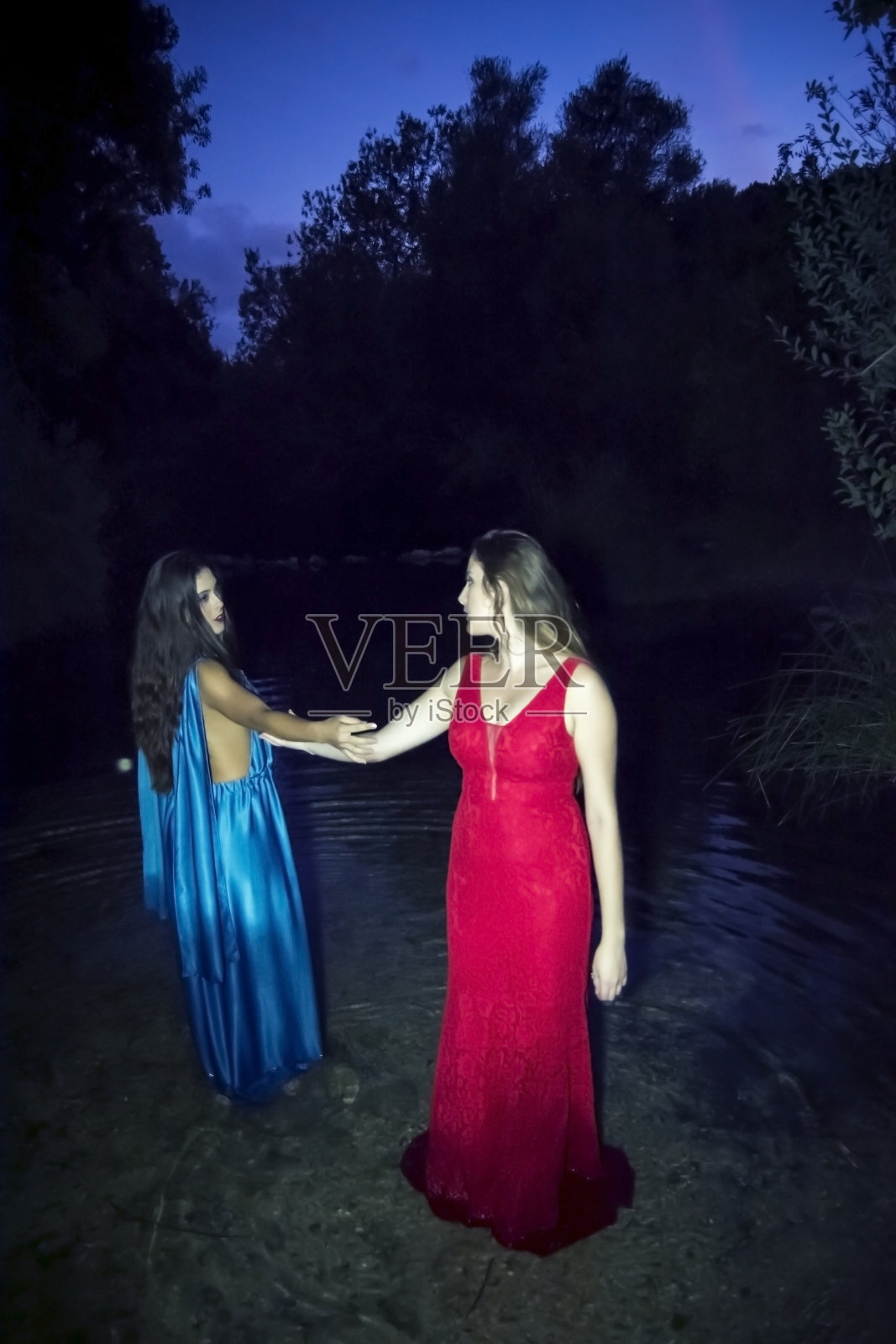 两个穿着晚礼服的漂亮女人站在山河的岸边照片摄影图片