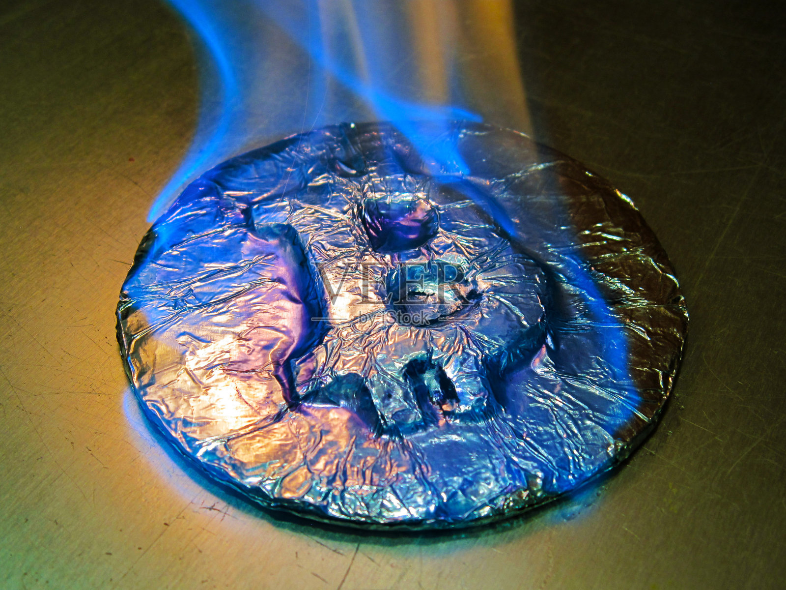 比特币着火了。真正的硬币燃烧着蓝色的火焰，象征着价格的暴涨或临界下跌照片摄影图片
