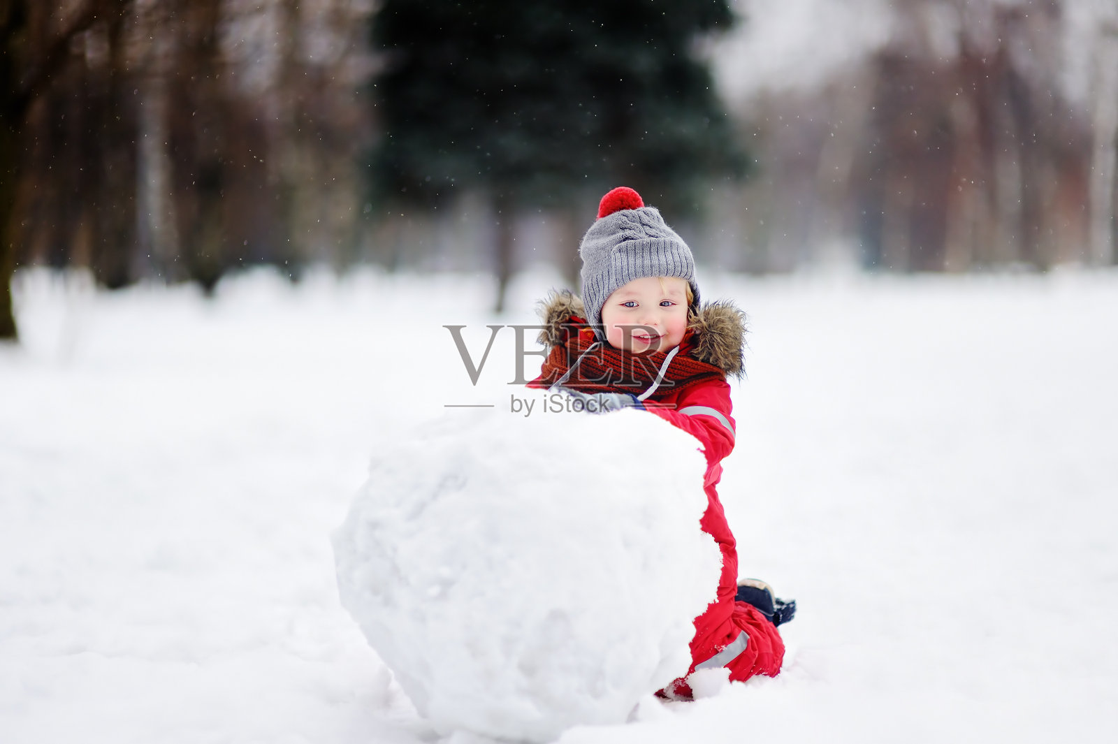 小男孩穿着红色的冬装和雪人玩照片摄影图片