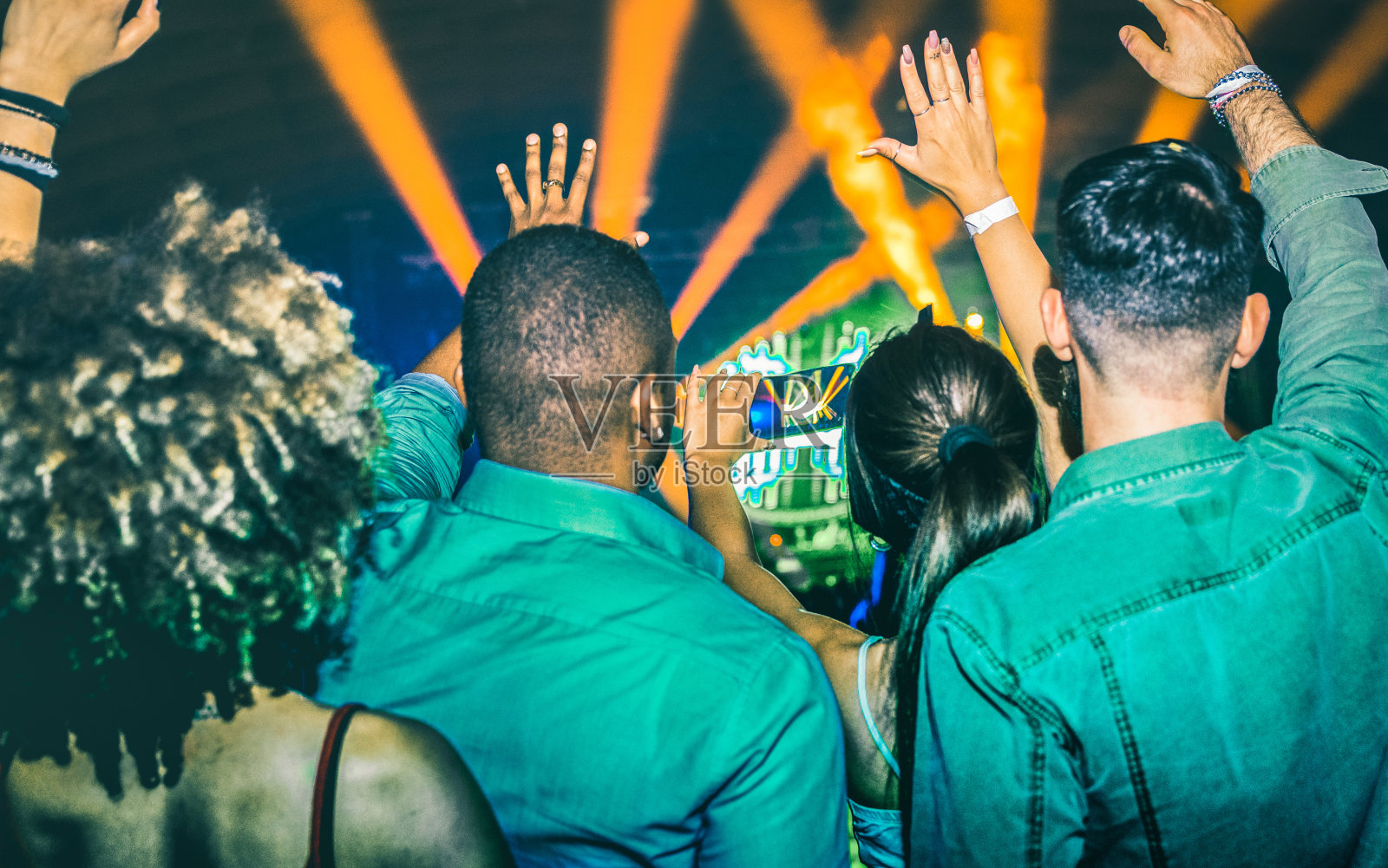 年轻人在夜总会跳舞-手在激光秀灯在夜总会后派对-夜生活概念与后派对人群庆祝dj音乐会节日活动-蓝绿色和橙色滤镜照片摄影图片