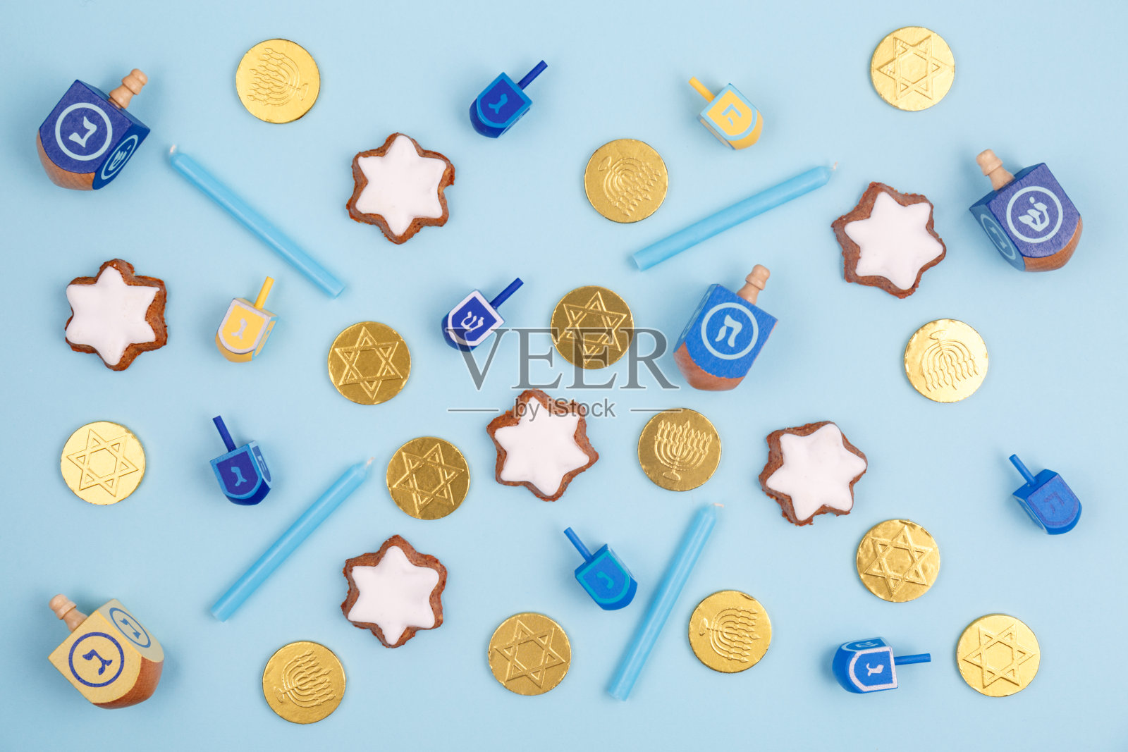蓝色背景，多色陀螺，梅诺拉蜡烛和巧克力硬币。光明节和犹太节日的概念。照片摄影图片