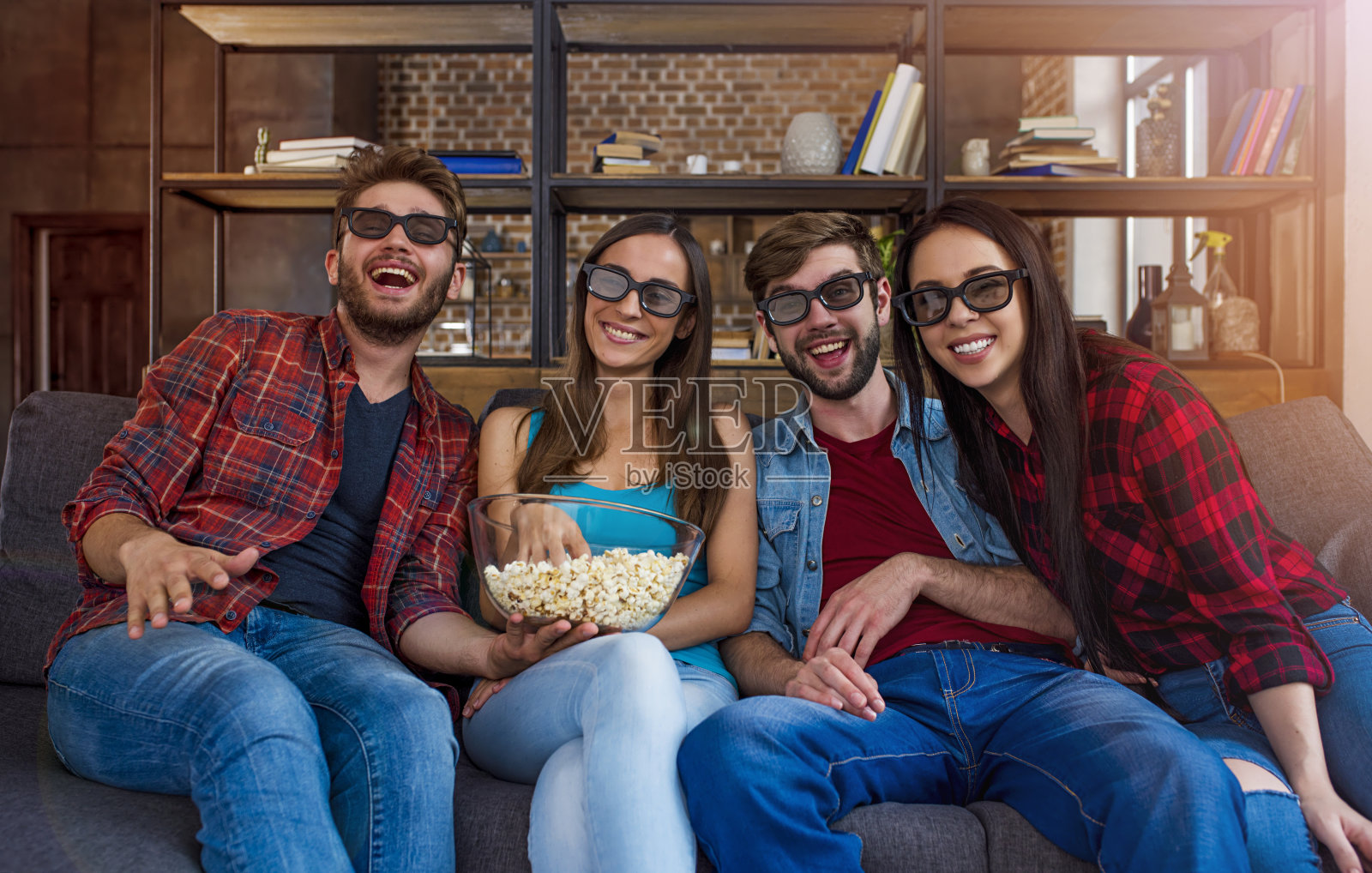 四个好朋友坐在沙发上吃着爆米花，戴着3d眼镜看一部很酷的电影照片摄影图片