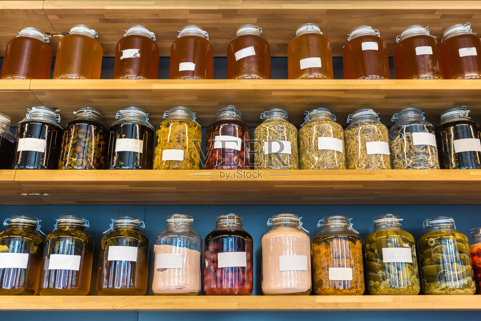 木架上的玻璃罐中成排的腌制食品，适合食物或餐厅主题概念照片摄影图片