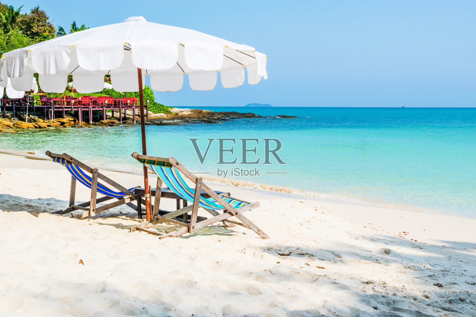 泰国Samed岛海滩上的彩色椅子和白色雨伞。照片摄影图片