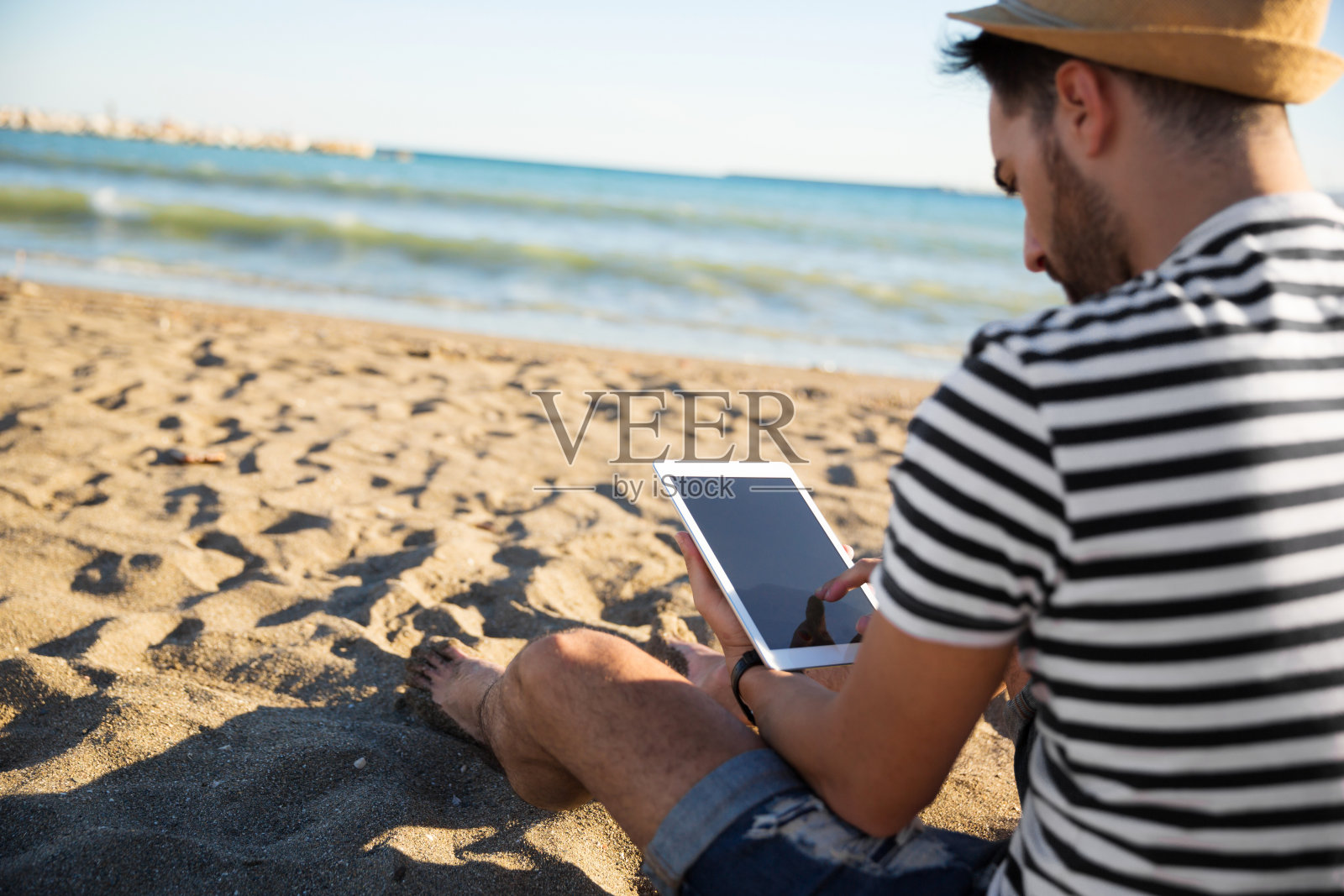 一个男人坐在沙滩上看电子书照片摄影图片