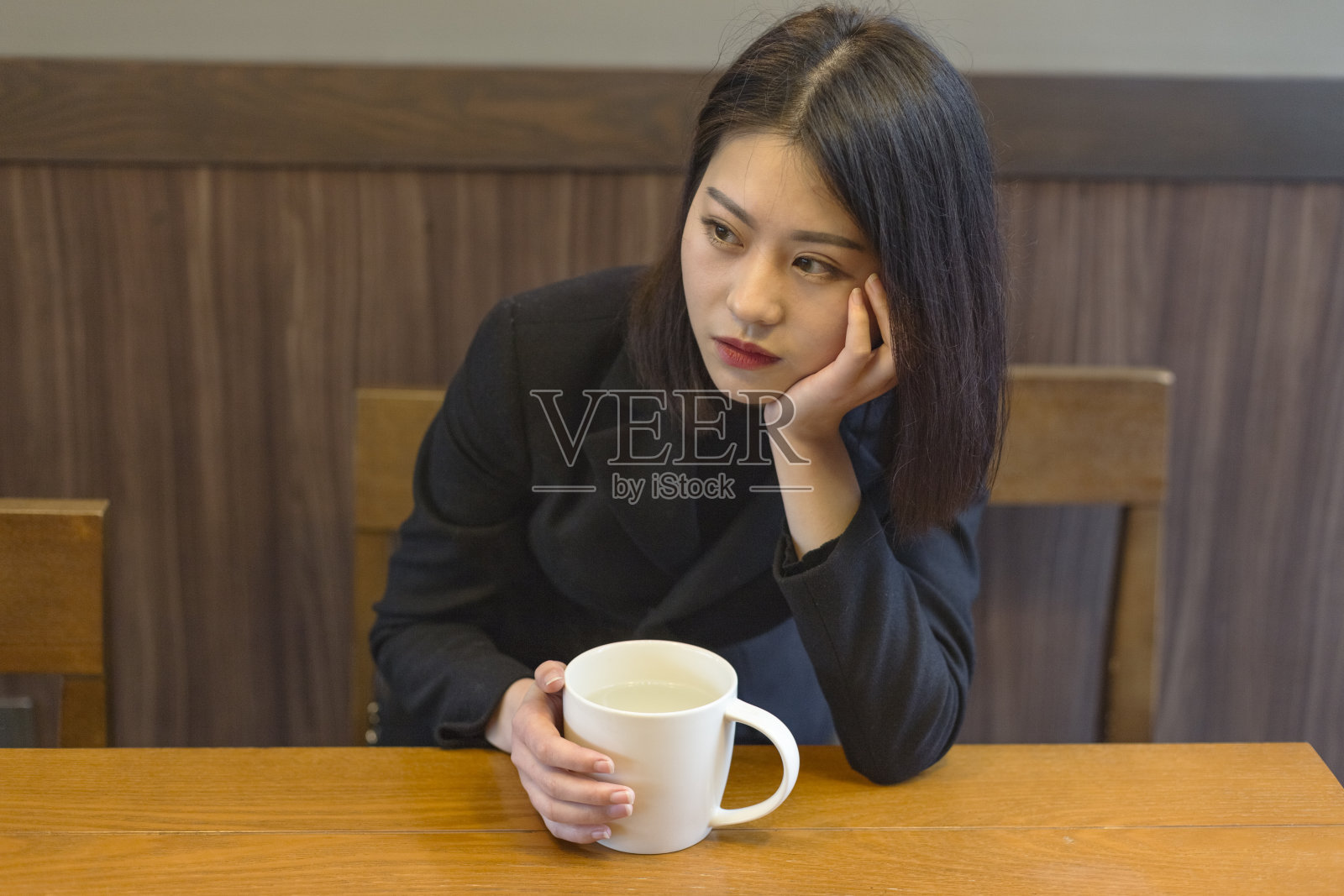一个沉思的女人在咖啡馆拿着一杯咖啡的肖像照片摄影图片