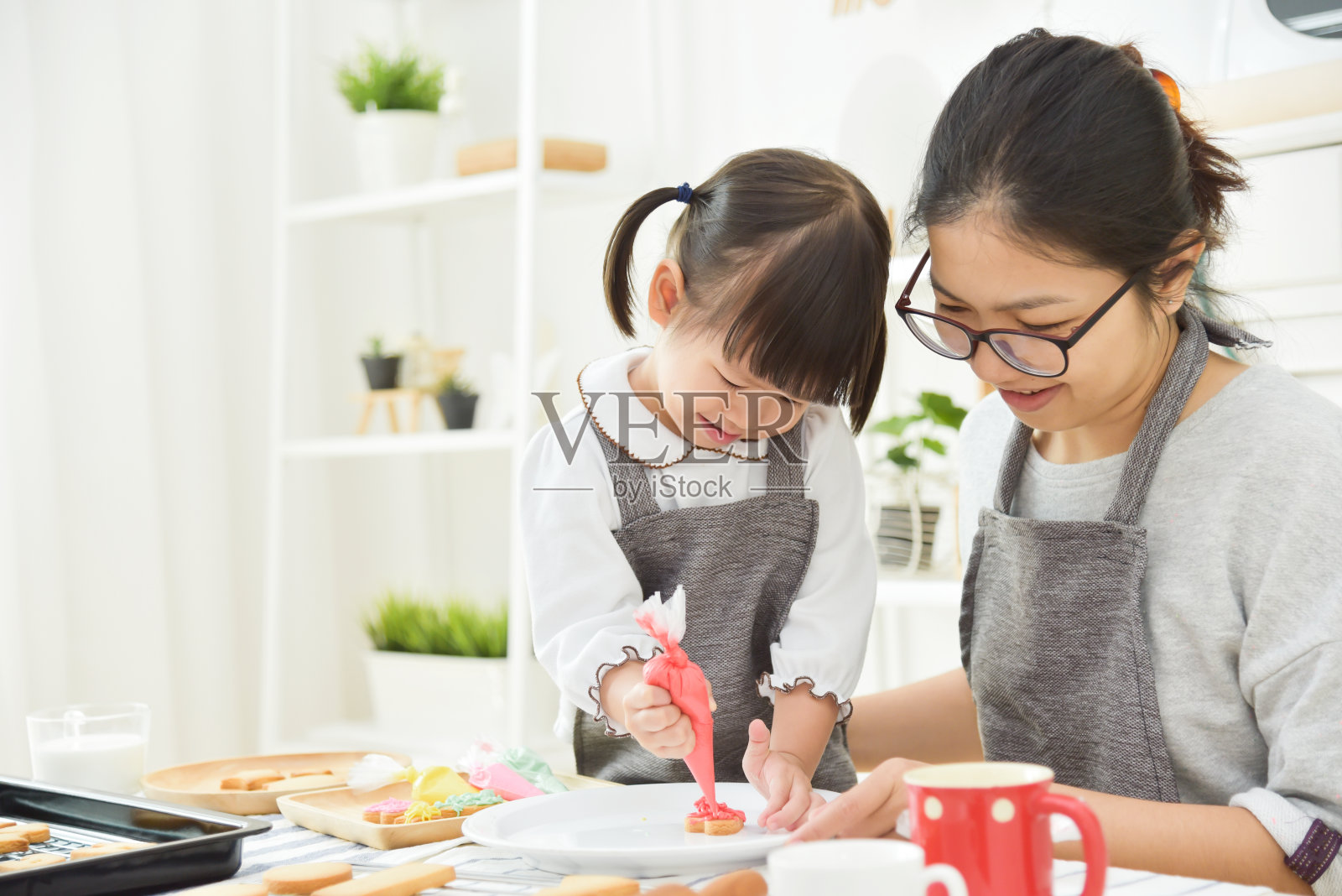 亚洲小孩和年轻的母亲装饰饼干。照片摄影图片