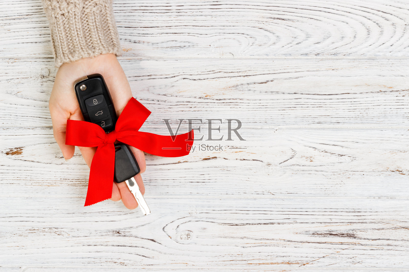 女人手里拿着带红色蝴蝶结的车钥匙。送一辆车作为礼物照片摄影图片