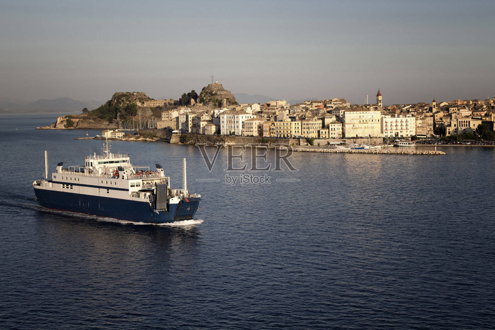 鸟瞰图科孚市(希腊岛)和一艘渡船离开。照片摄影图片