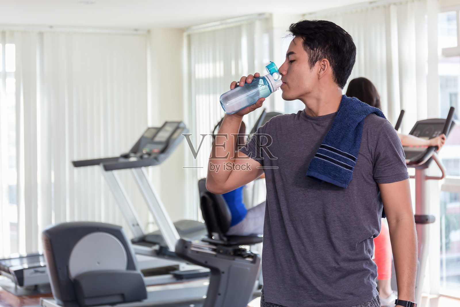快乐健康的人在健身房喝水。运动后。照片摄影图片
