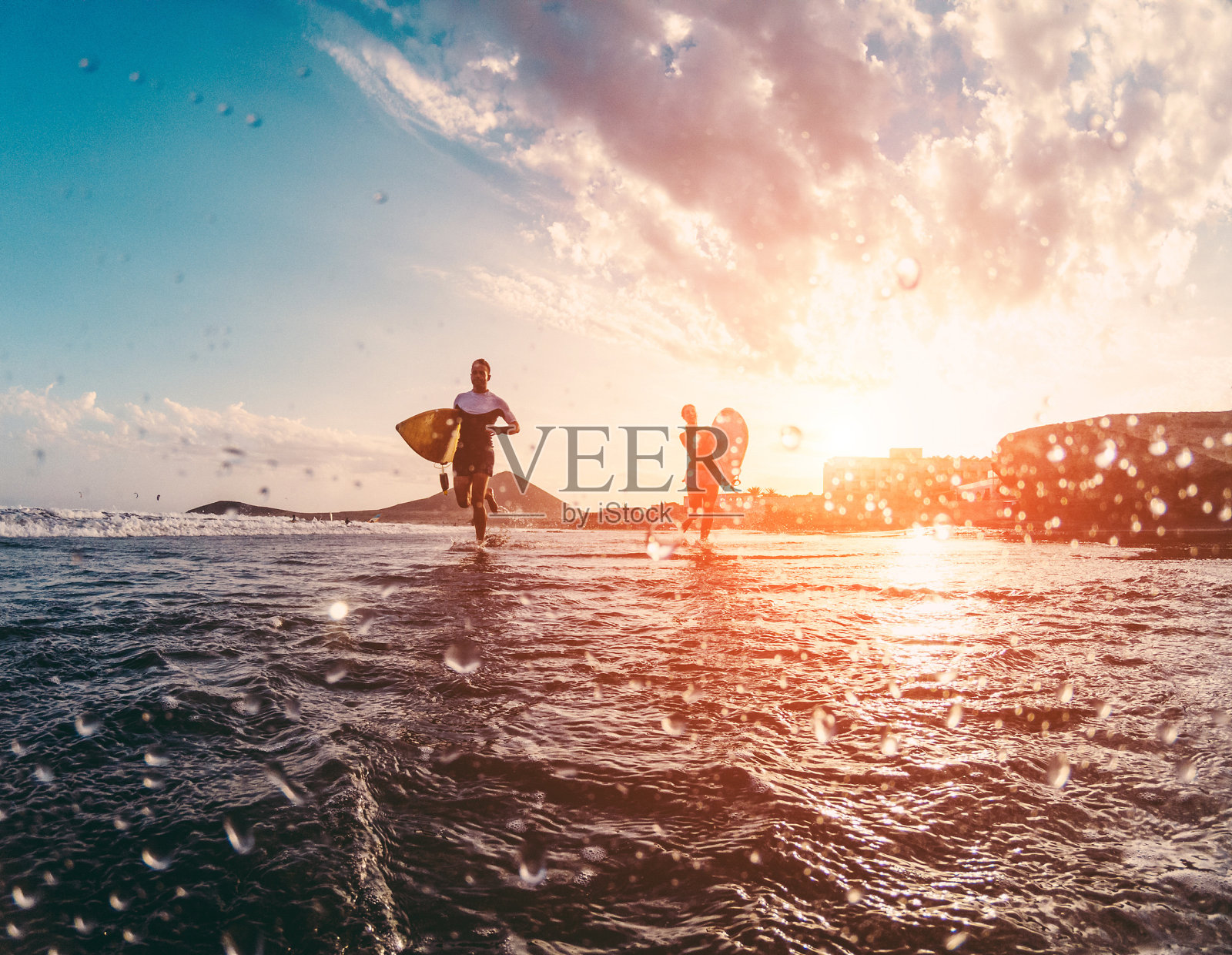 快乐的冲浪爱好者在海滩上跑步-运动的人在阳光明媚的日子里玩-极限运动，旅行和度假的概念-关注身体的轮廓-镜头上的水照片摄影图片