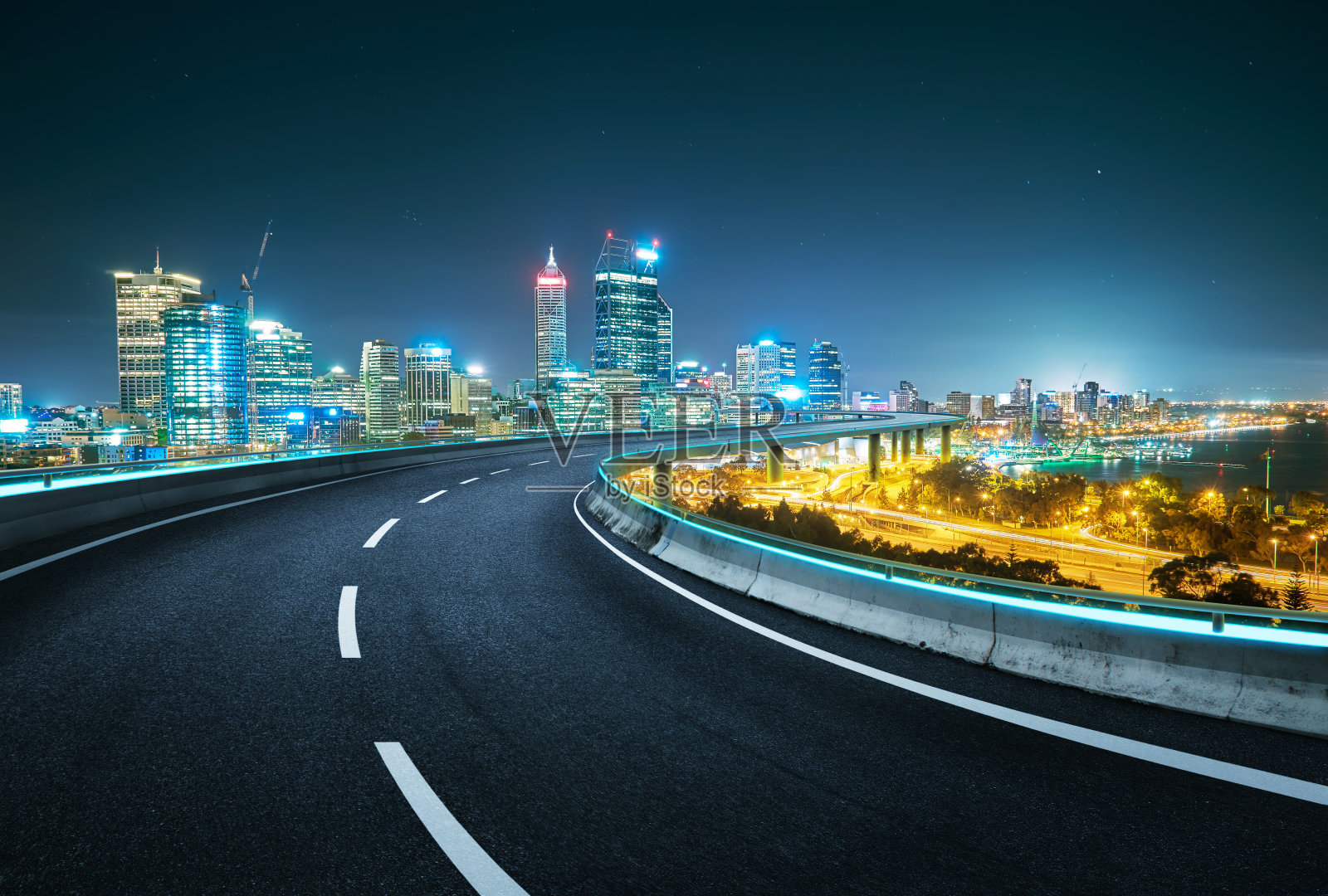 以现代城市为背景的蓝色霓虹灯设计高速公路立交桥。夜景。照片摄影图片