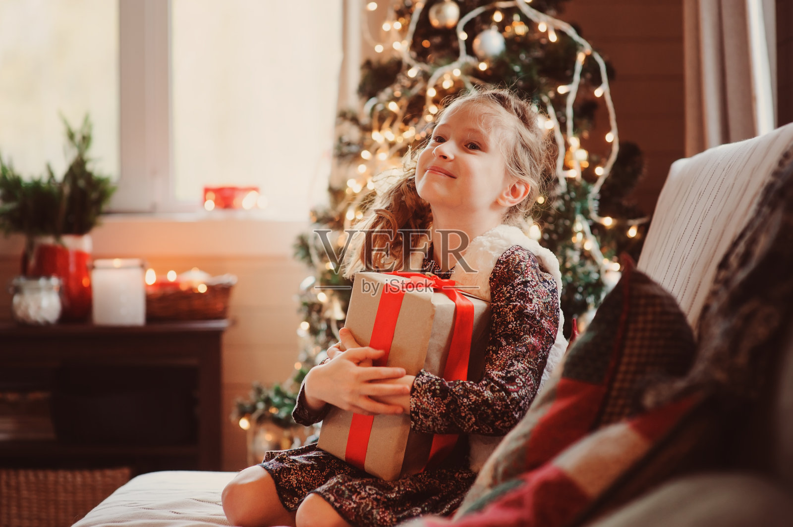 快乐的孩子女孩拿着礼物圣诞节或新年在家里装饰树的背景照片摄影图片