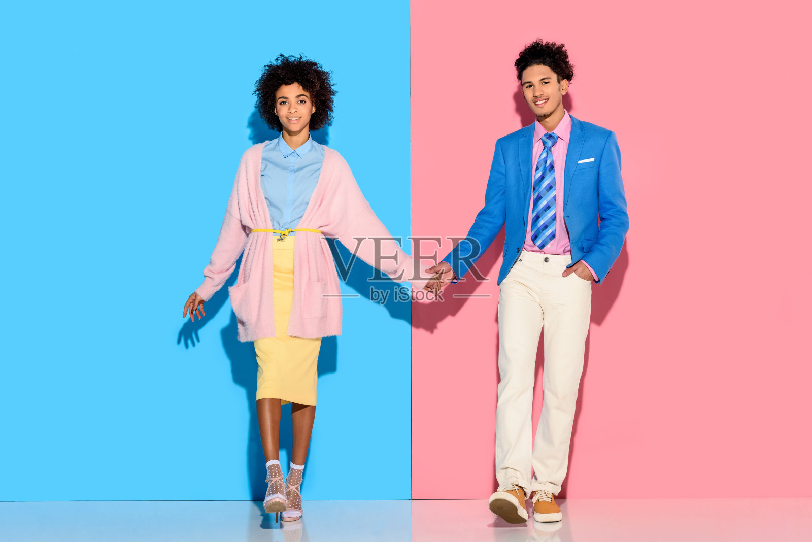 情侣手牵着手，背景是粉色和蓝色照片摄影图片