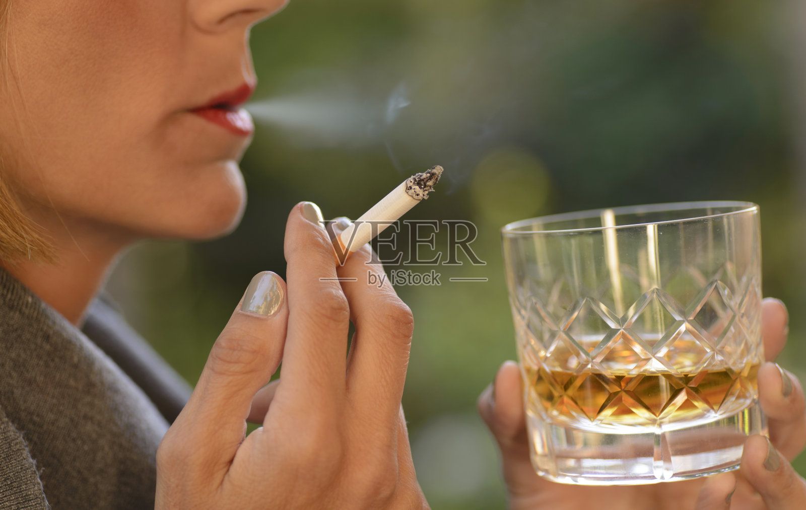 一个女人喝着威士忌，抽着烟。照片摄影图片
