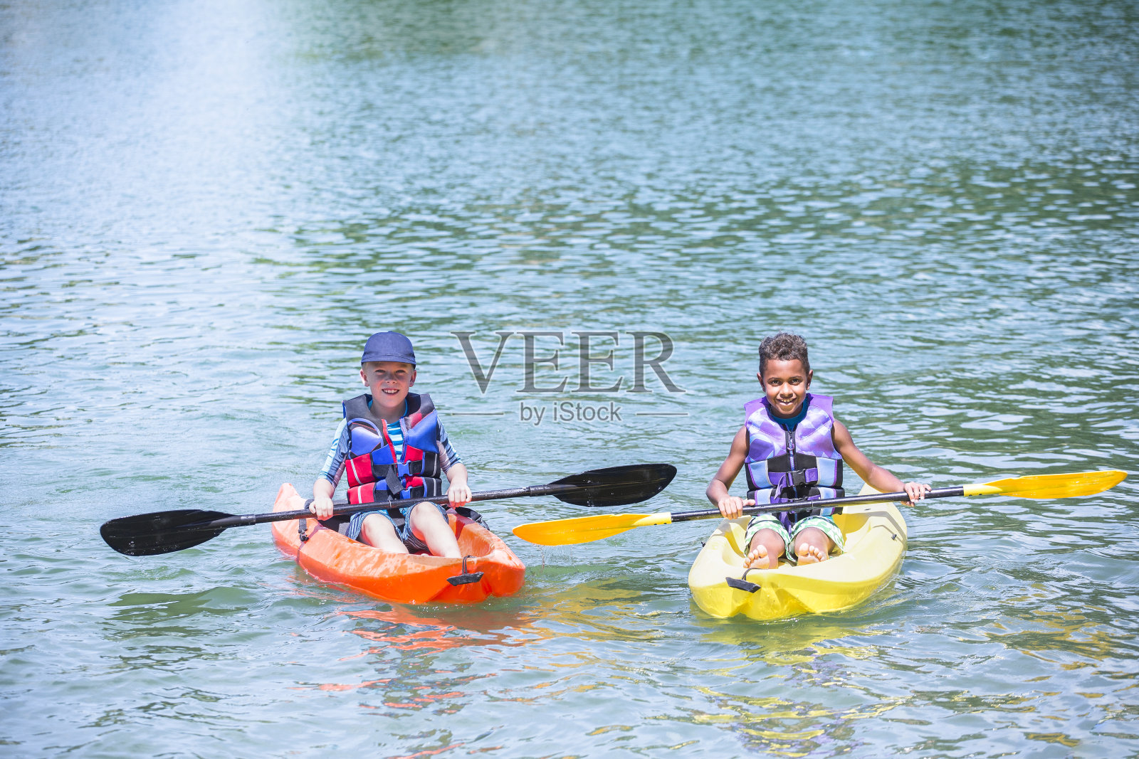 两个不同的小男孩在美丽的湖上划皮划艇照片摄影图片