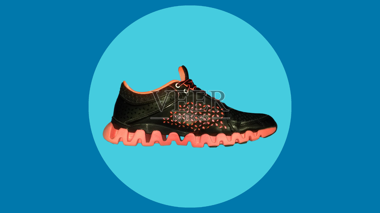 现代橙色/黑色跑鞋，鞋子孤立在蓝色背景，概念，地方的文本。照片摄影图片