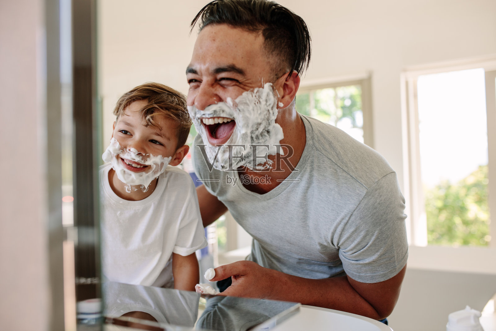 快乐的父亲和儿子在享受剃须的乐趣照片摄影图片