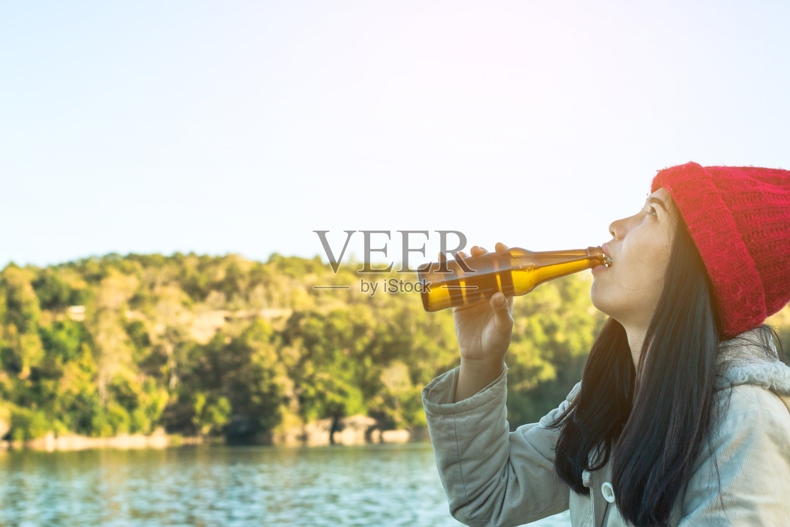 女人坐着喝啤酒放松假日与美丽的自然。照片摄影图片
