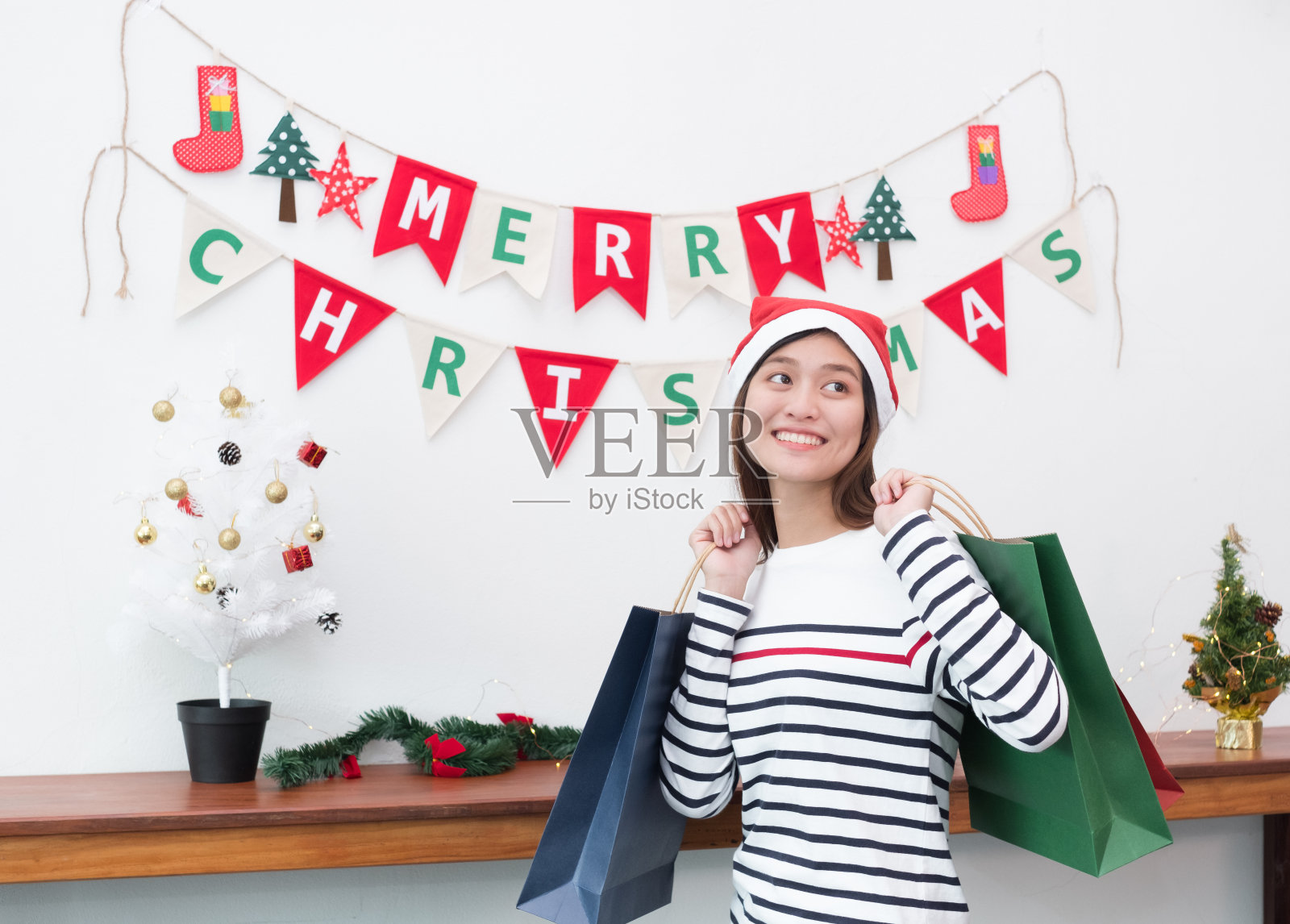 快乐微笑亚洲女人拿着许多购物袋在派对上，购买圣诞和新年礼物，假期购物，礼物赠送的概念。照片摄影图片