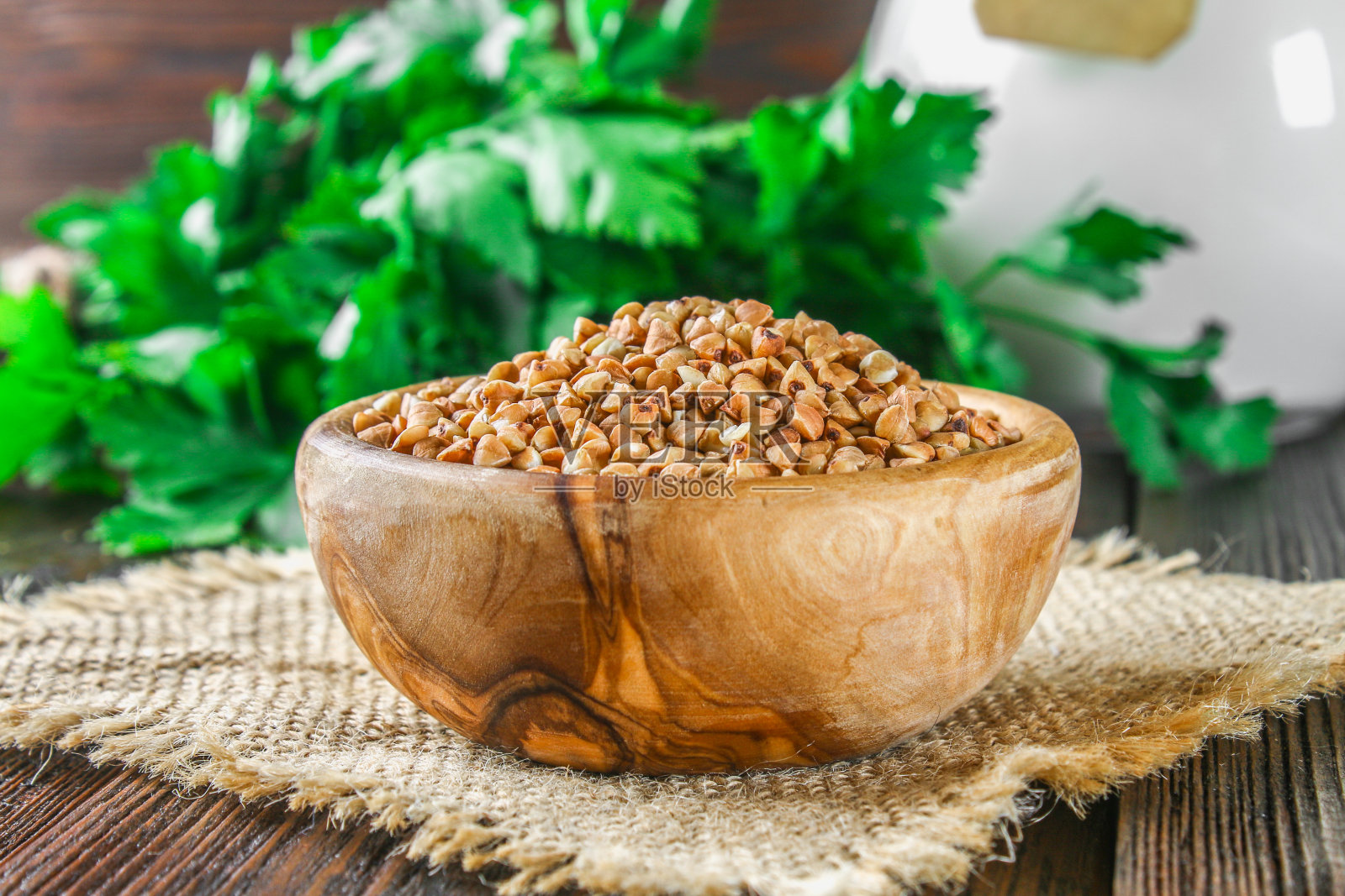 木碗里装着生荞麦，木质背景上用粗麻布做了一个勺子。健康的减肥食品。照片摄影图片