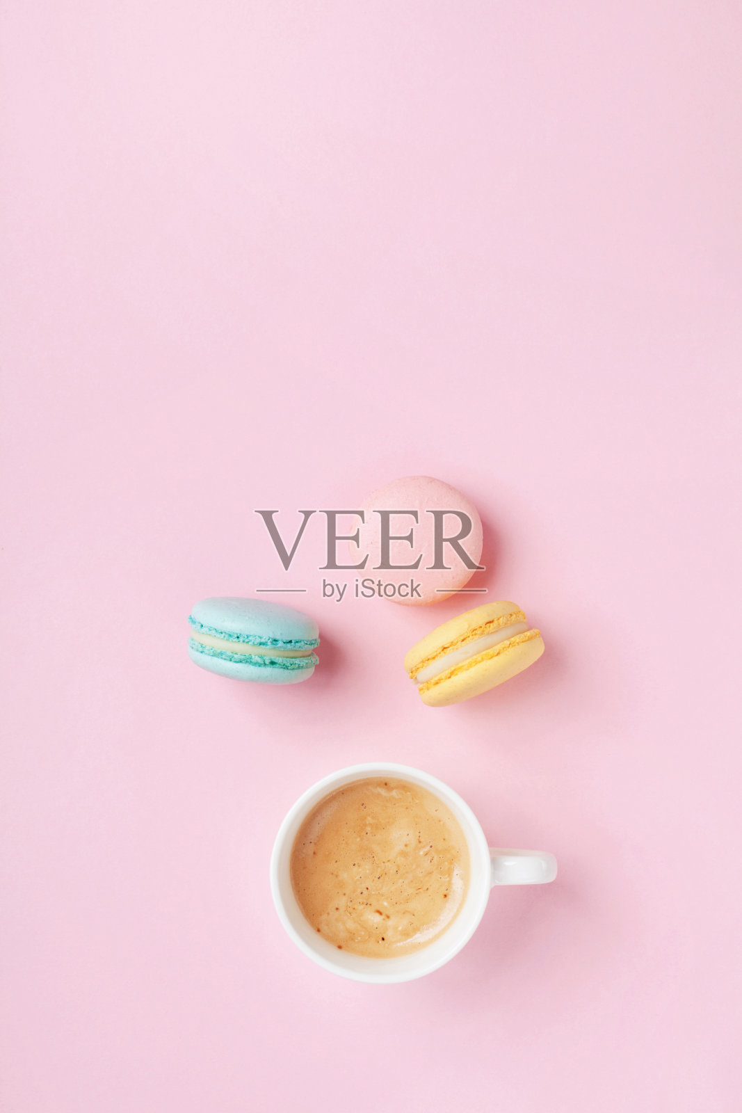 早上一杯咖啡和彩色的蛋糕马卡龙在淡粉色的背景俯视图。温馨的早餐。时尚公寓。照片摄影图片