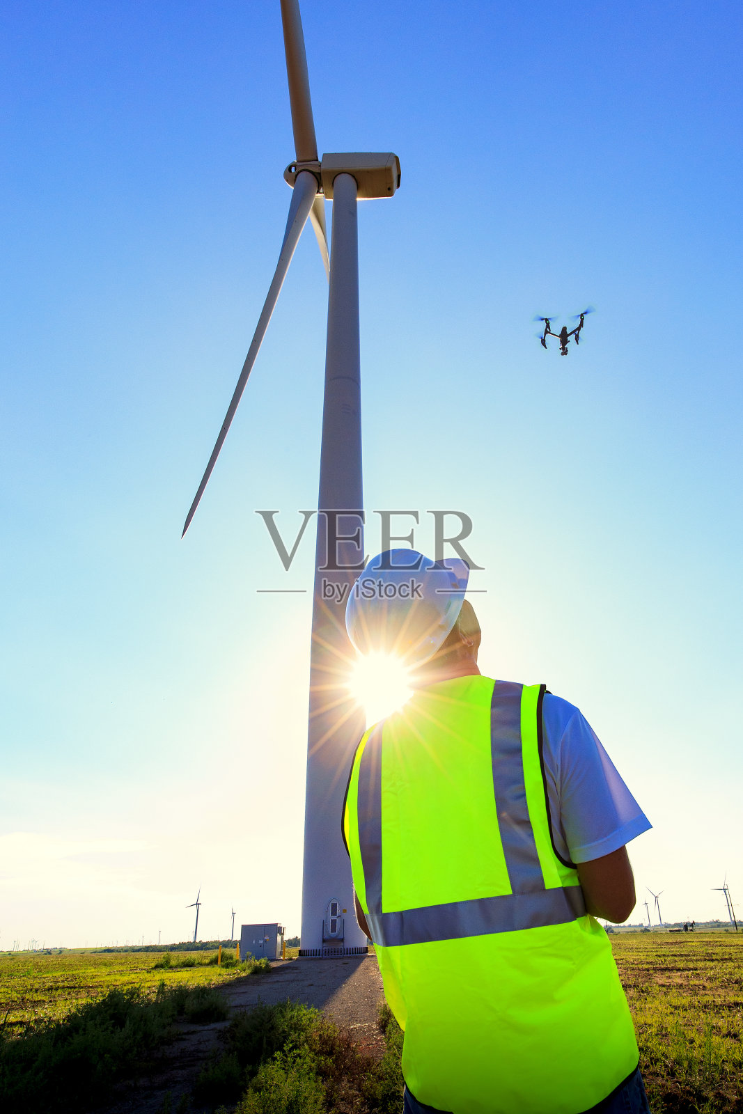 无人机驾驶员在检查风力发电机时操作无人机照片摄影图片