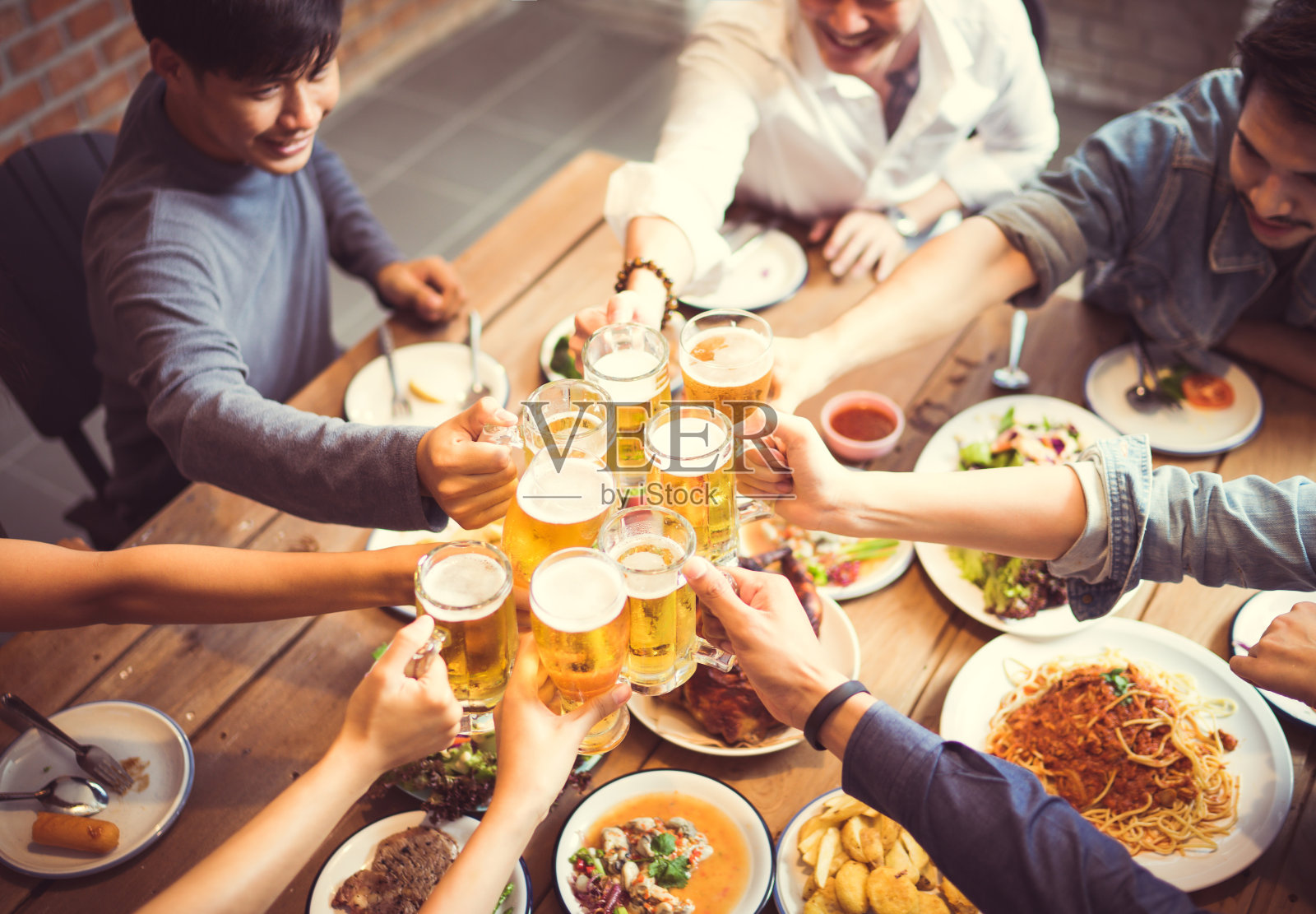 亚洲人庆祝节日，他们碰杯，啤酒和晚餐快乐。俯视图照片摄影图片
