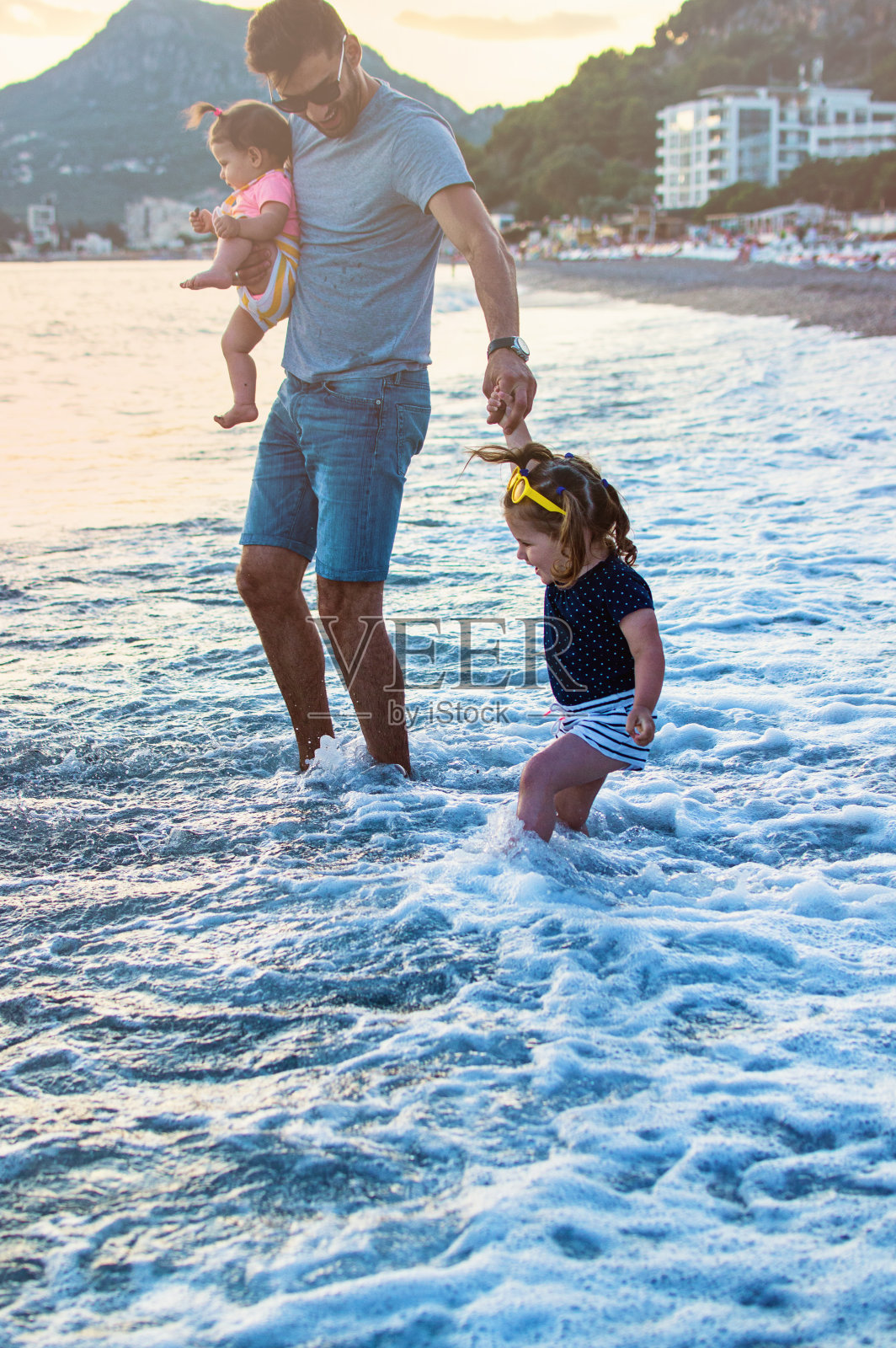 幸福的年轻的家庭在日落时在海滩上跑步照片摄影图片