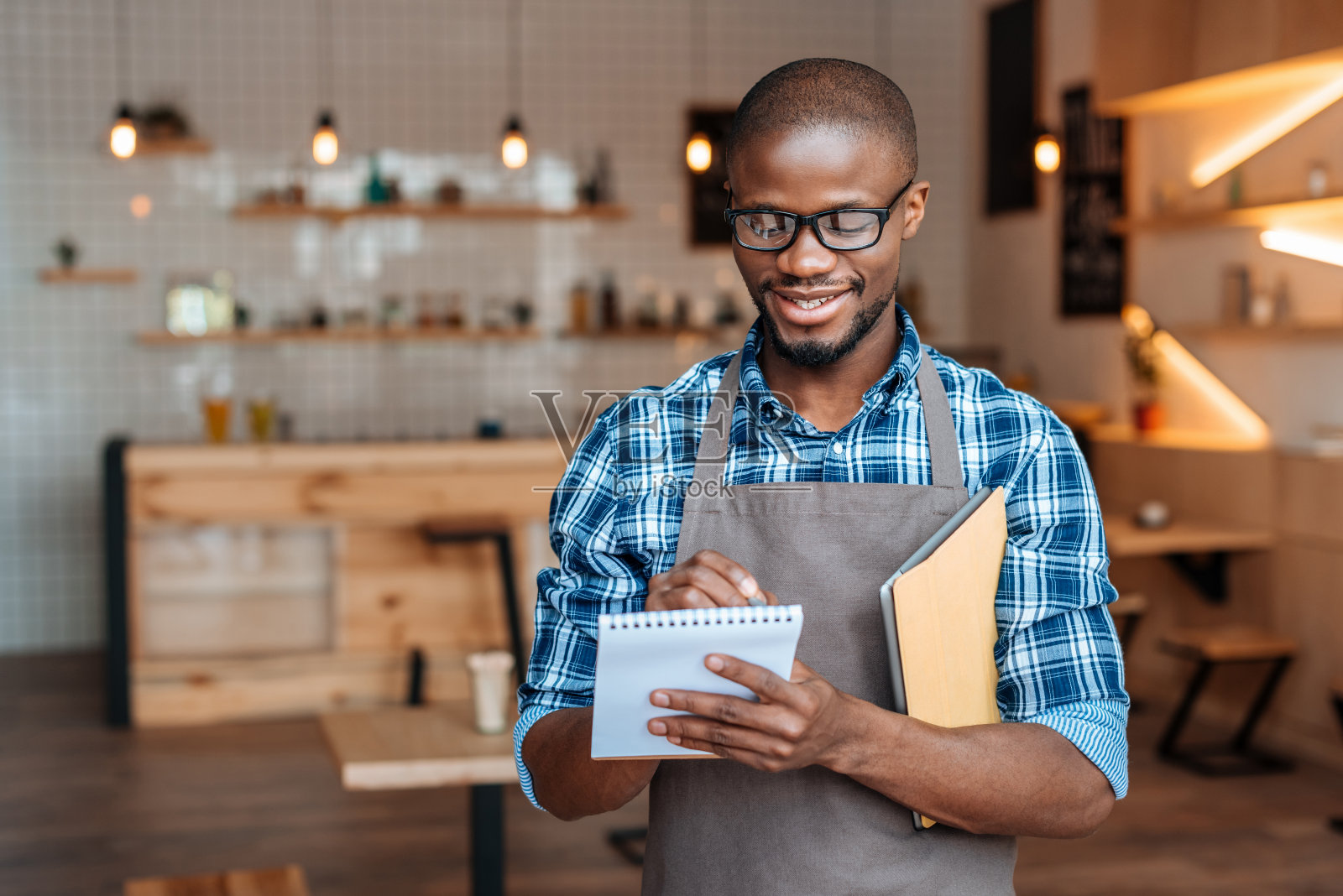 英俊微笑的非裔美国侍者在咖啡店用记事本和平板电脑点菜照片摄影图片