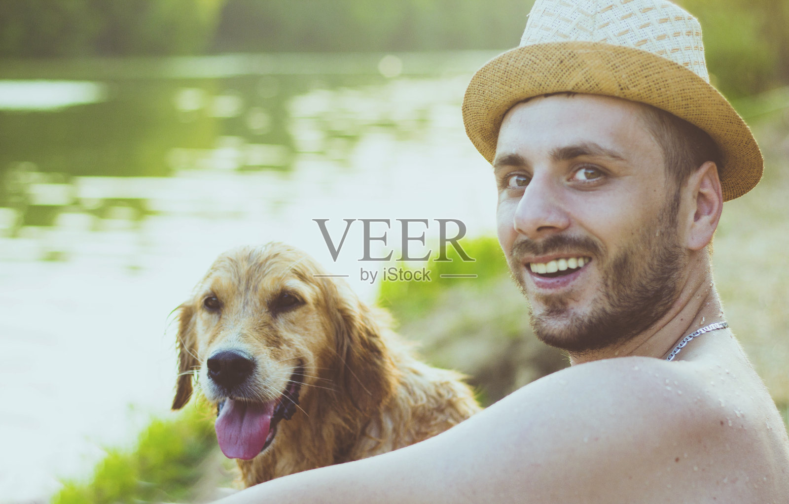 友谊的概念，人和金毛猎犬一起坐在沙滩上照片摄影图片