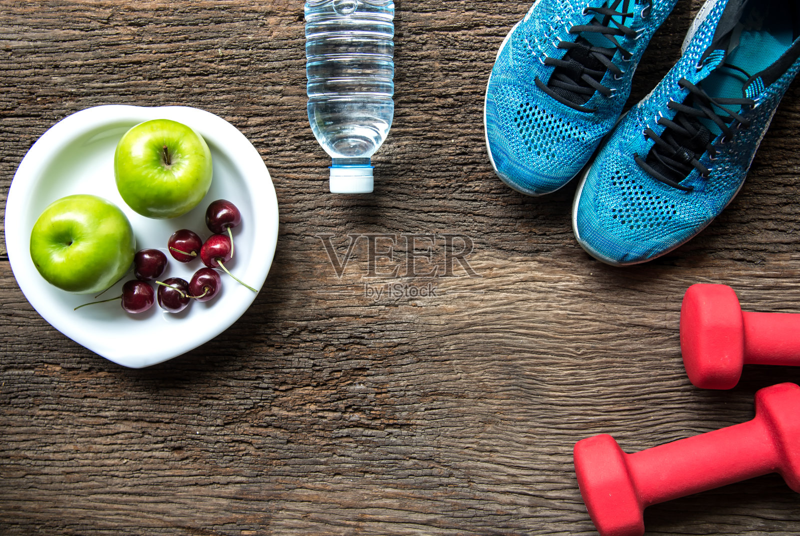 健康的生活方式运动器材健身，运动鞋，青苹果，新鲜的水和健康的食物在老木头的背景。健康的概念。照片摄影图片