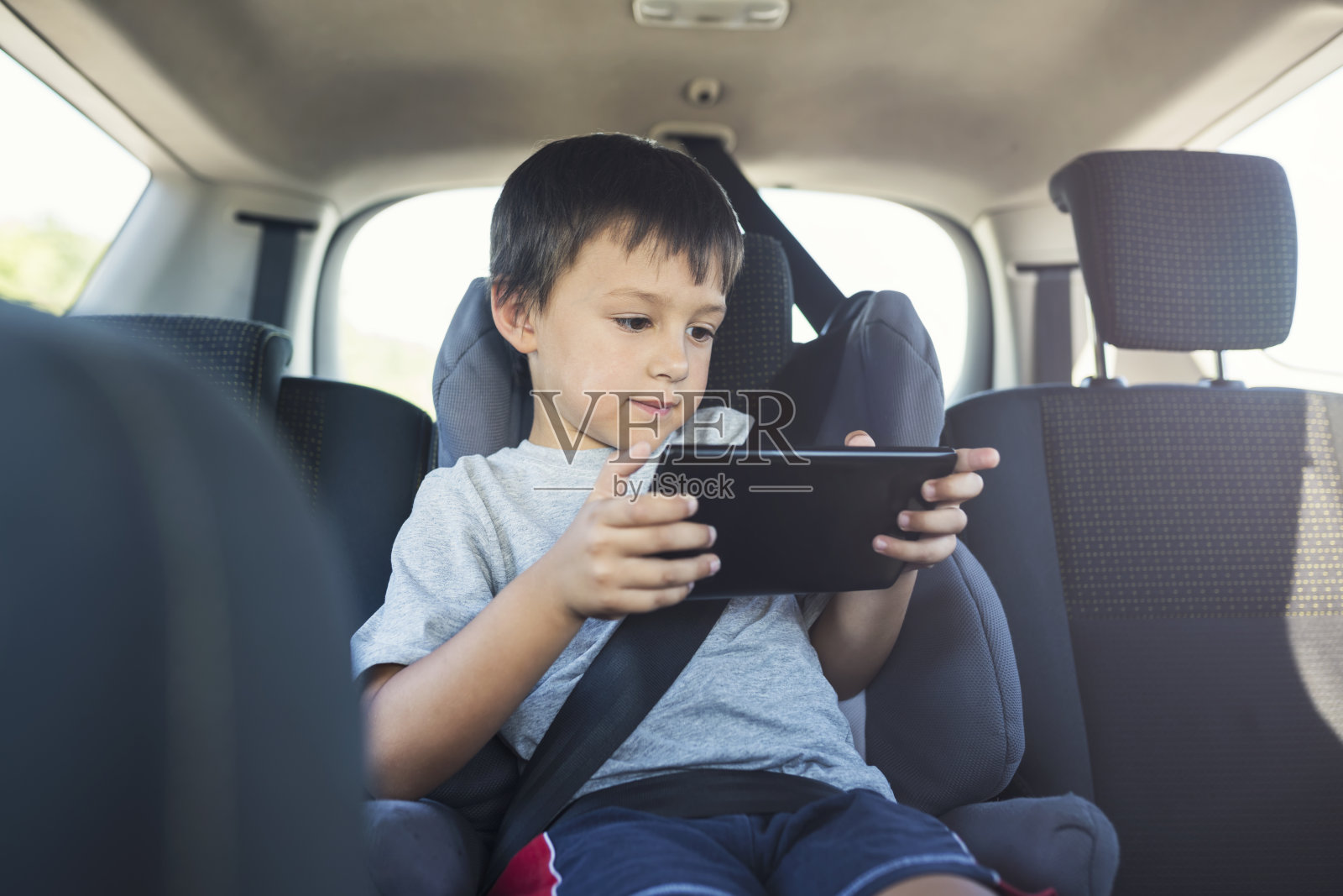 小男孩在车里玩平板电脑照片摄影图片