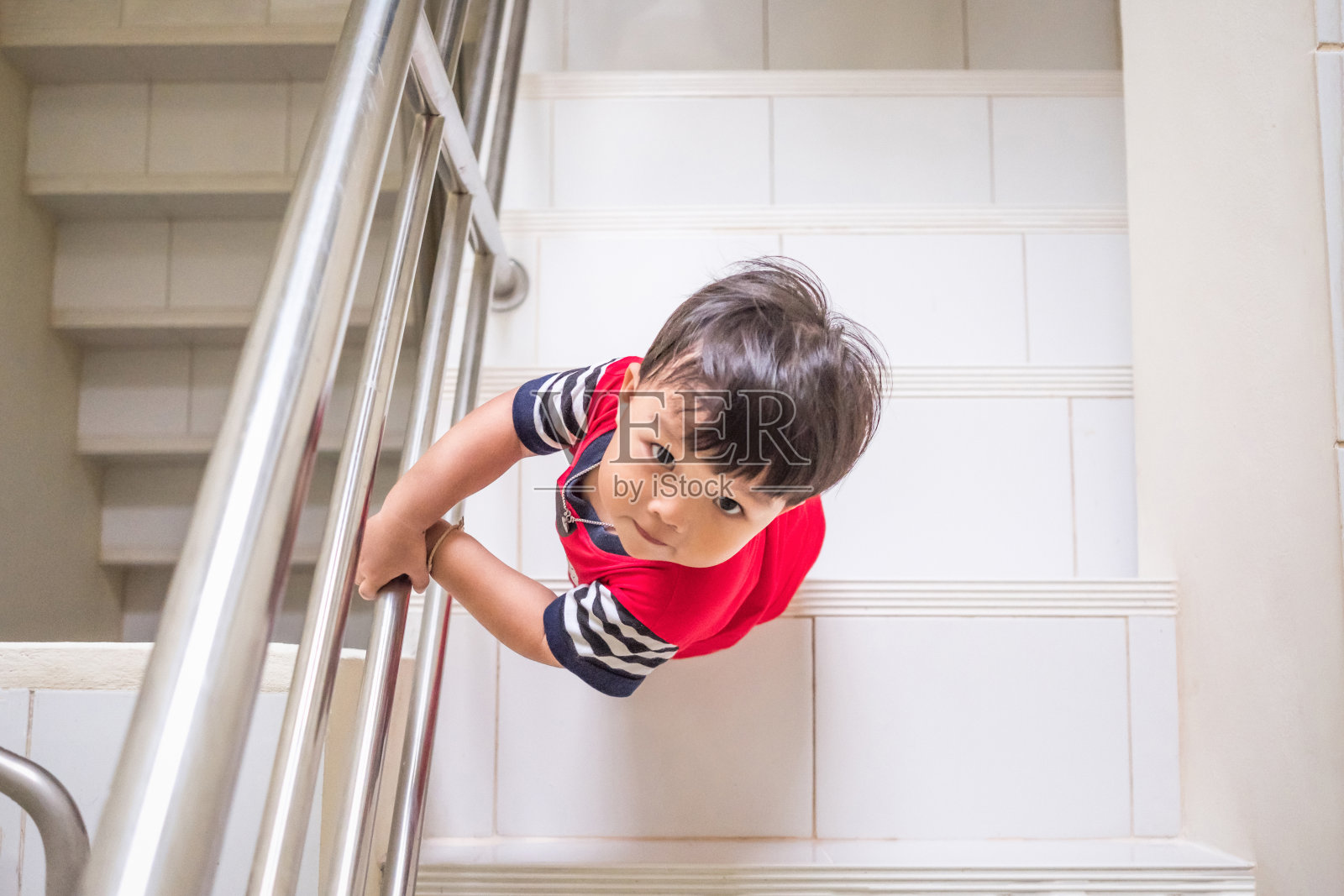 小男孩爬上楼梯从高角度看照片摄影图片