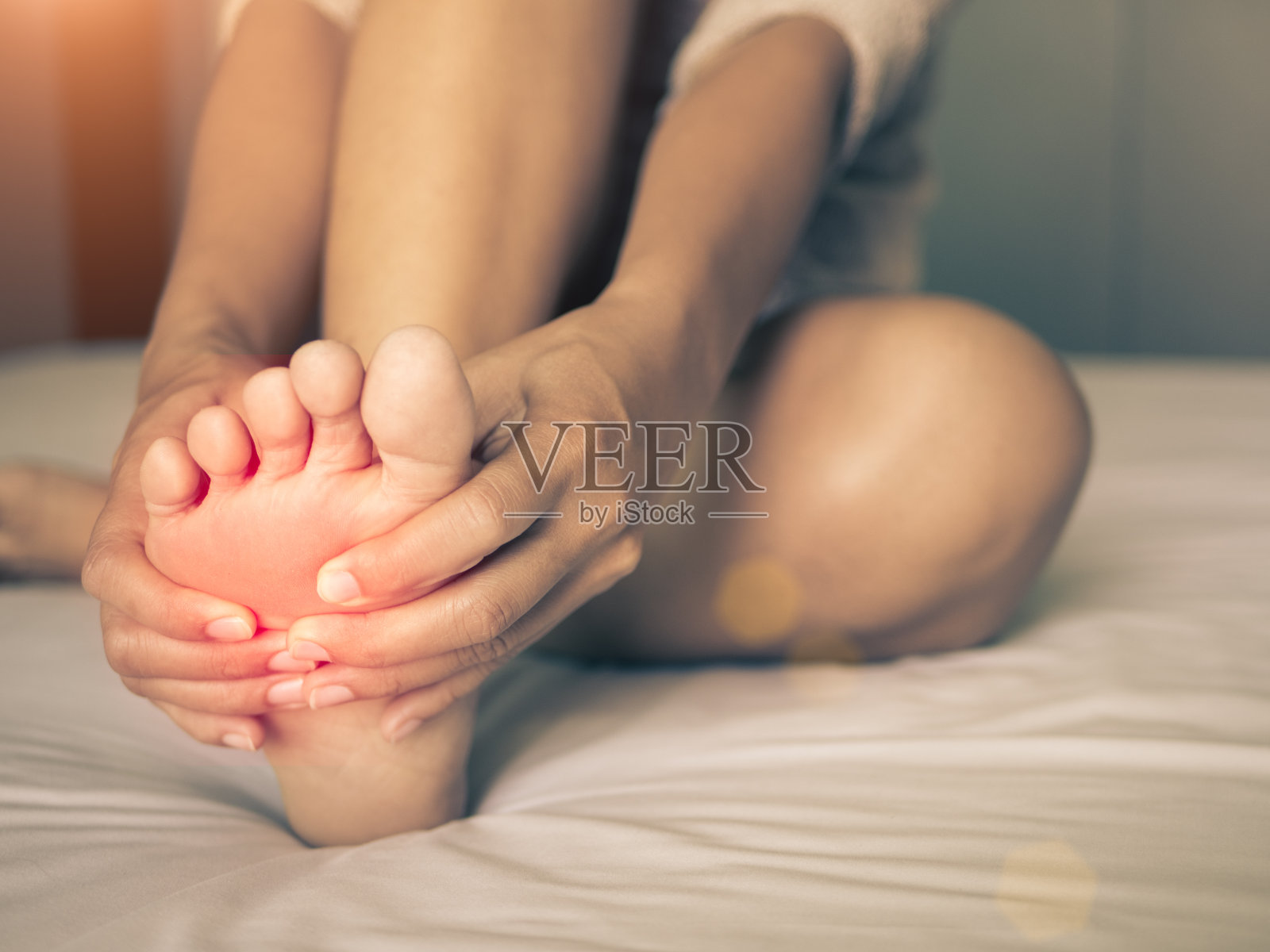 卫生保健的概念。一个女人在按摩她疼痛的脚，疼痛部位的红色高光照片摄影图片