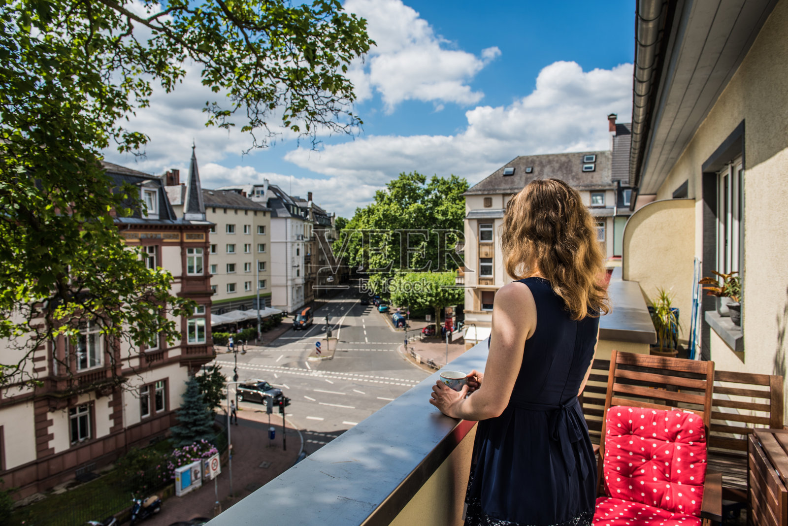 一个年轻女子站在一个阳光明媚的日子里，在家里的阳台上照片摄影图片