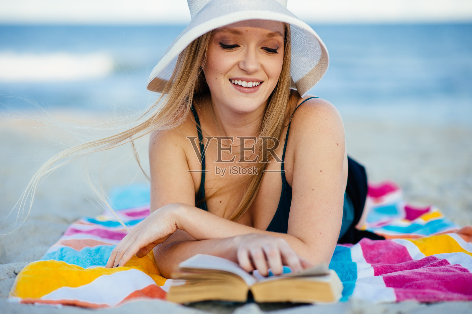 年轻女子在海滩上读书照片摄影图片