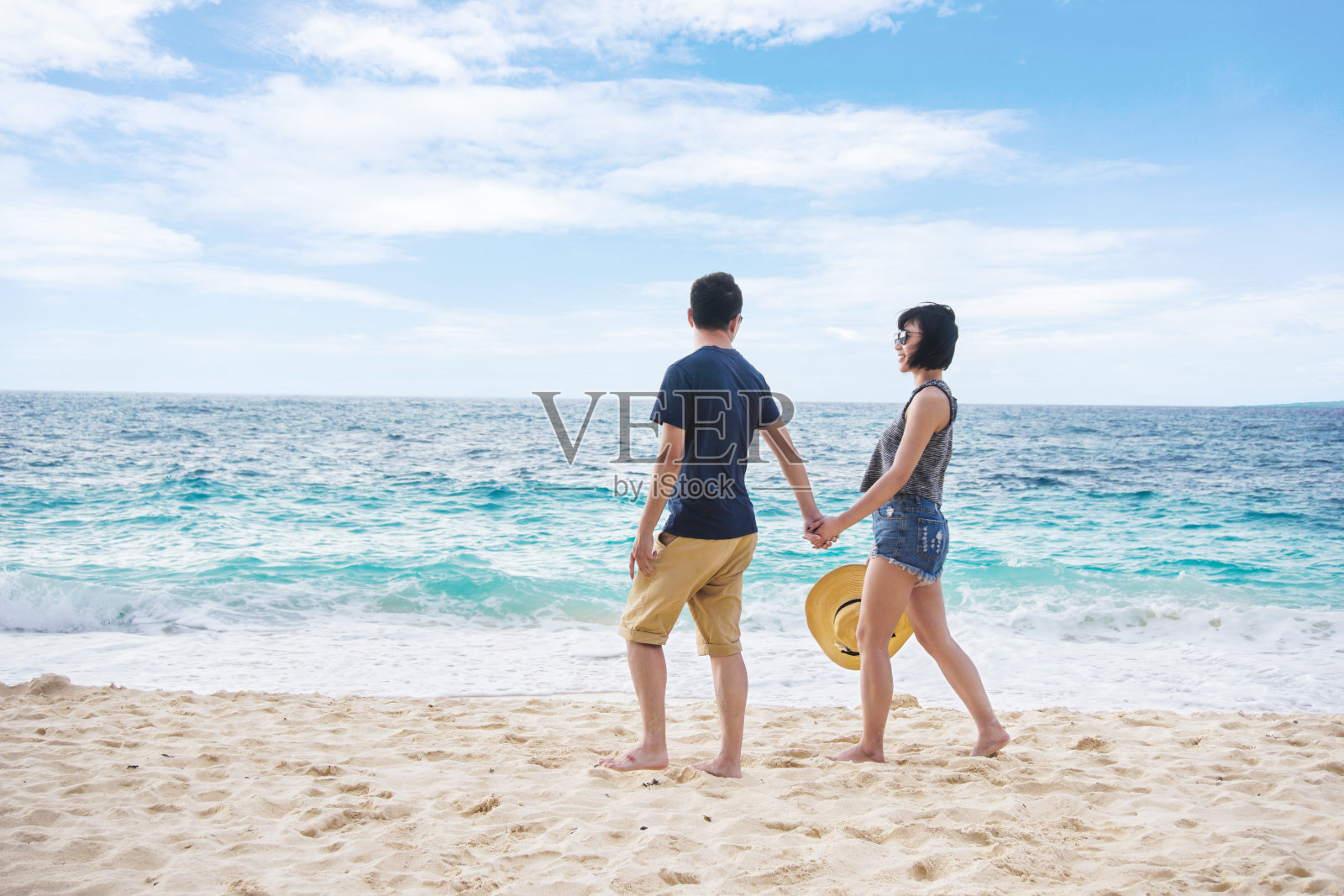年轻夫妇手牵着手在海滩上散步照片摄影图片