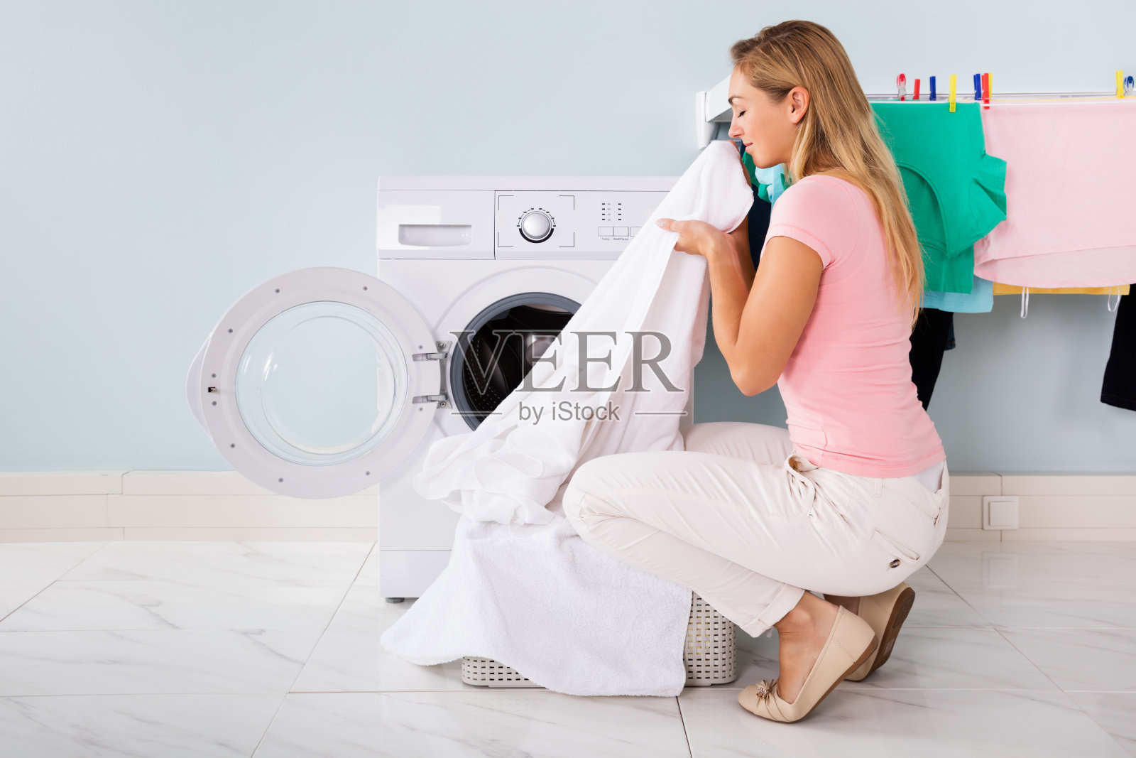 把洗好的衣服放在电子洗衣机旁边的女人照片摄影图片