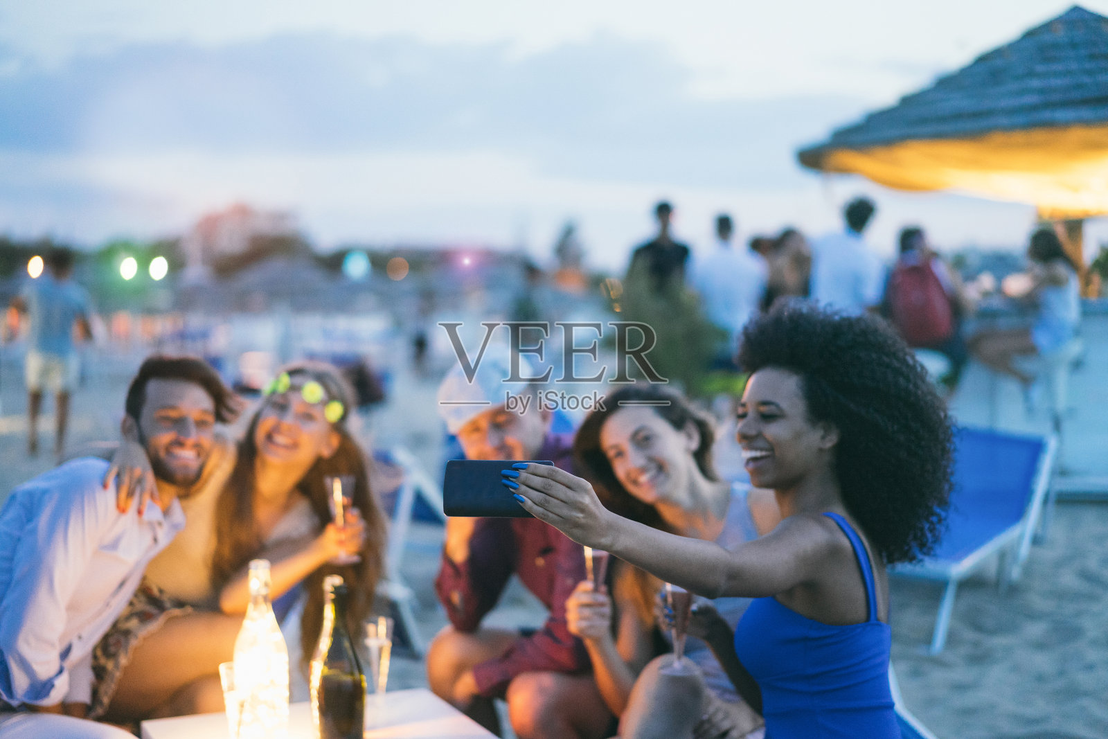 快乐的朋友与智能手机自拍在海滩派对户外-年轻人有乐趣在kiosk酒吧喝香槟-关注非洲女孩手机-青春和夏天的概念照片摄影图片
