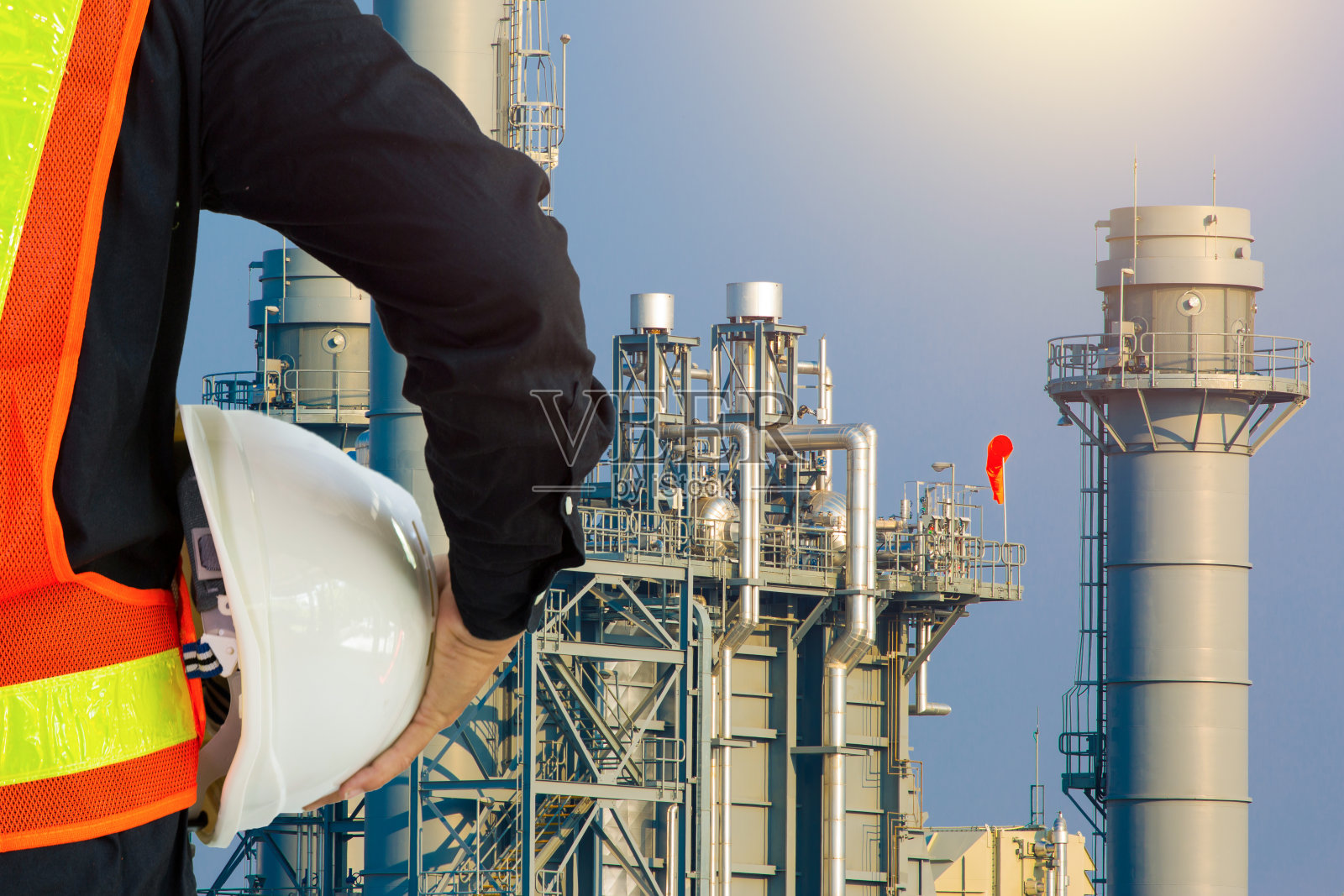 一名戴着白色安全帽的工程人员站在重石化工业炼油厂建筑结构前照片摄影图片