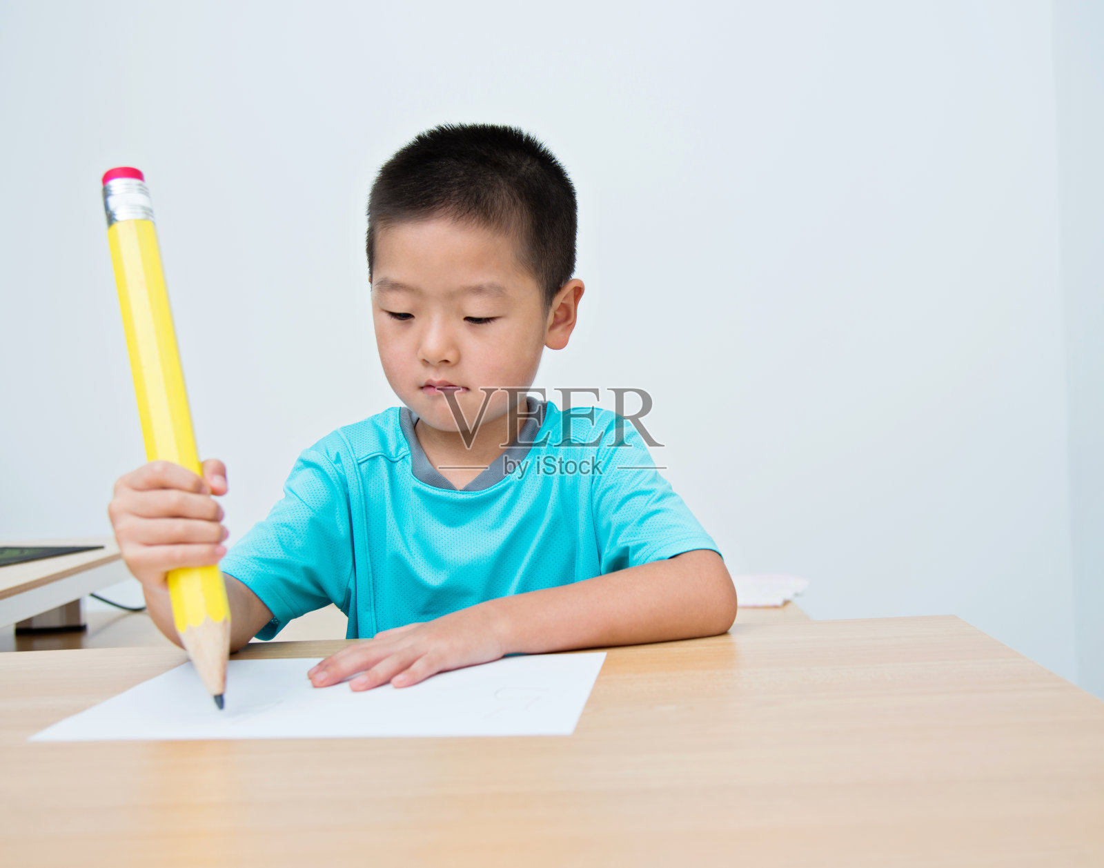 亚洲小男孩用一支大铅笔写字照片摄影图片