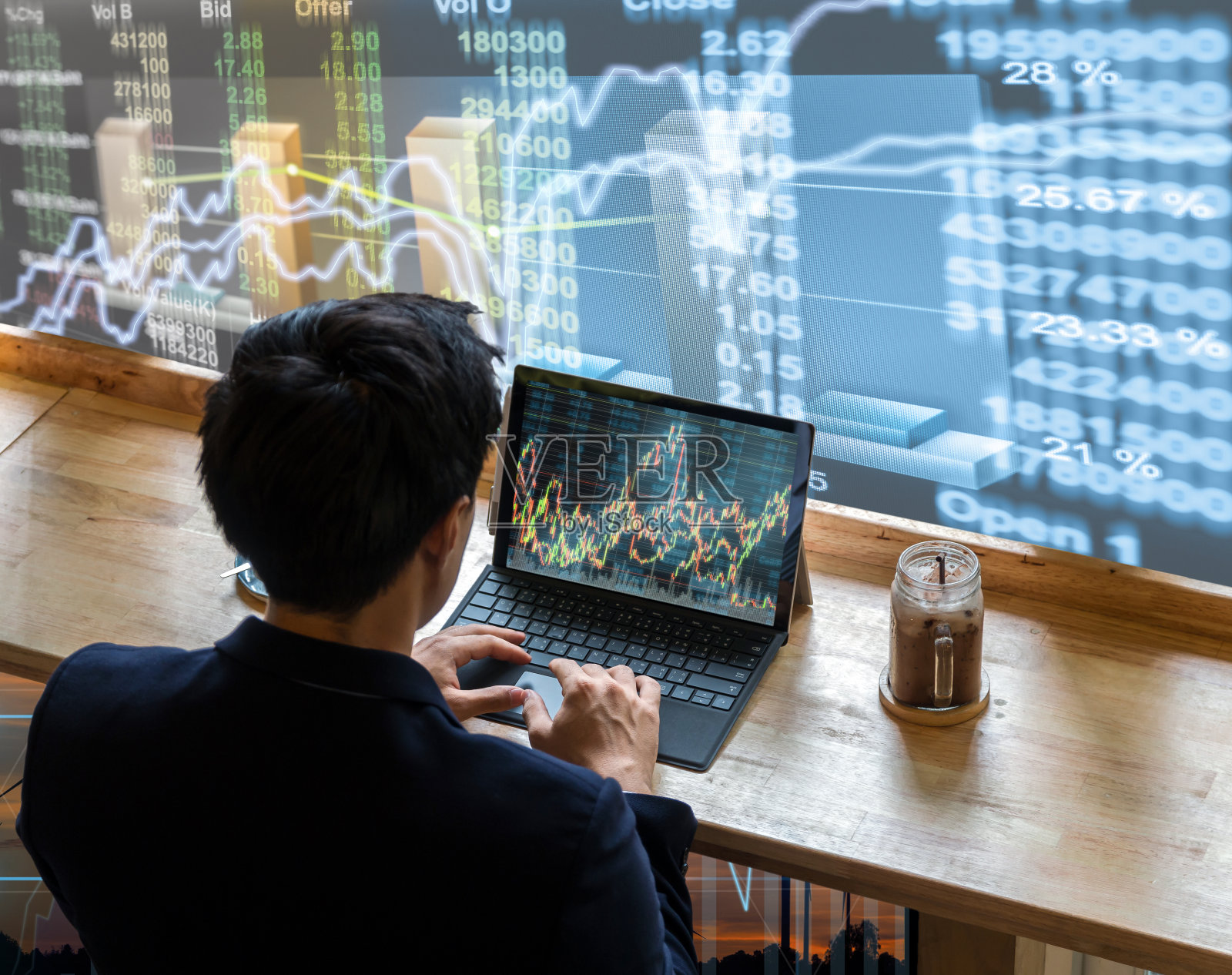 背面的商人坐在和使用电脑笔记本显示交易图形旁边的窗户玻璃上的股票市场图表背景，商业金融和交易概念照片摄影图片