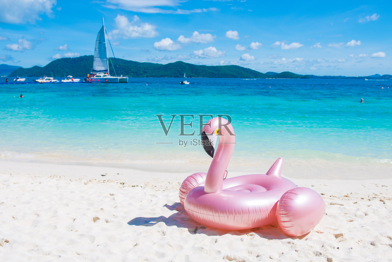 巨大的粉红色充气火烈鸟游泳池漂浮玩具在热带海滩上照片摄影图片