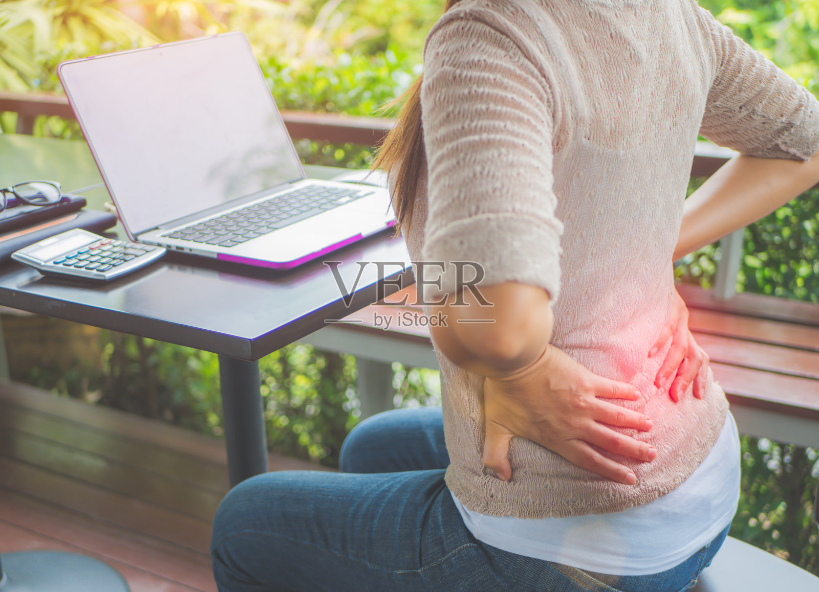 特写女人的手握着她的腰背部疼痛。办公室综合症和保健概念。照片摄影图片