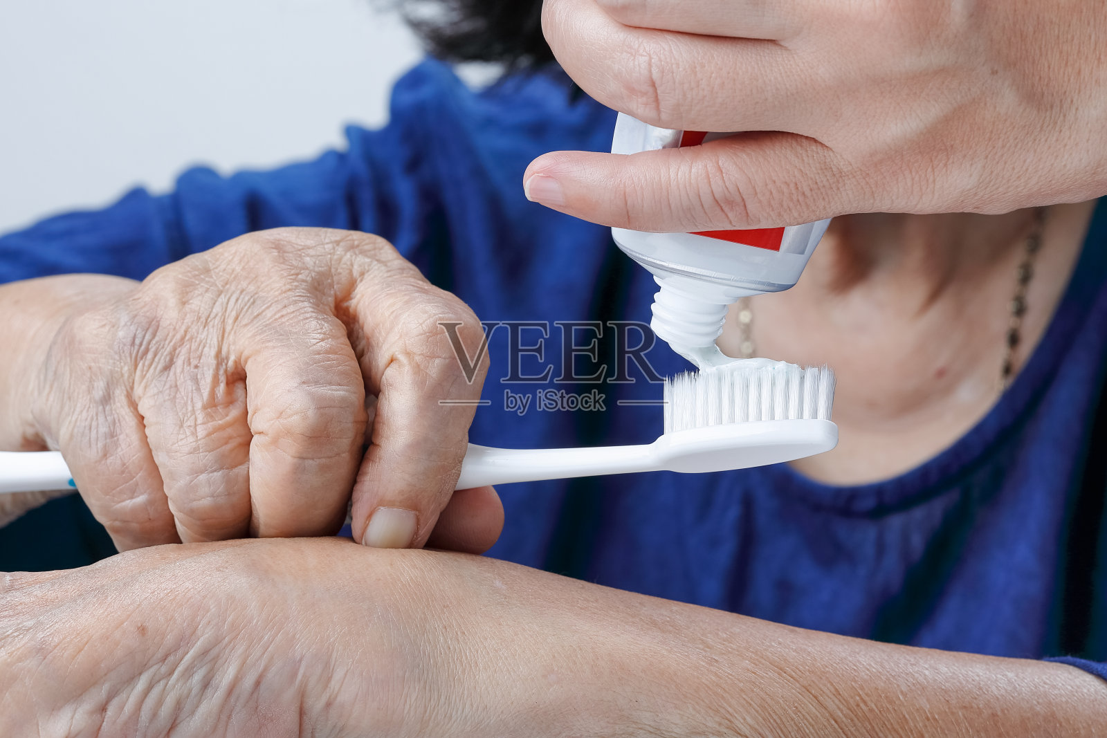 亚洲老年妇女试着用牙刷，手颤抖。牙齿健康照片摄影图片