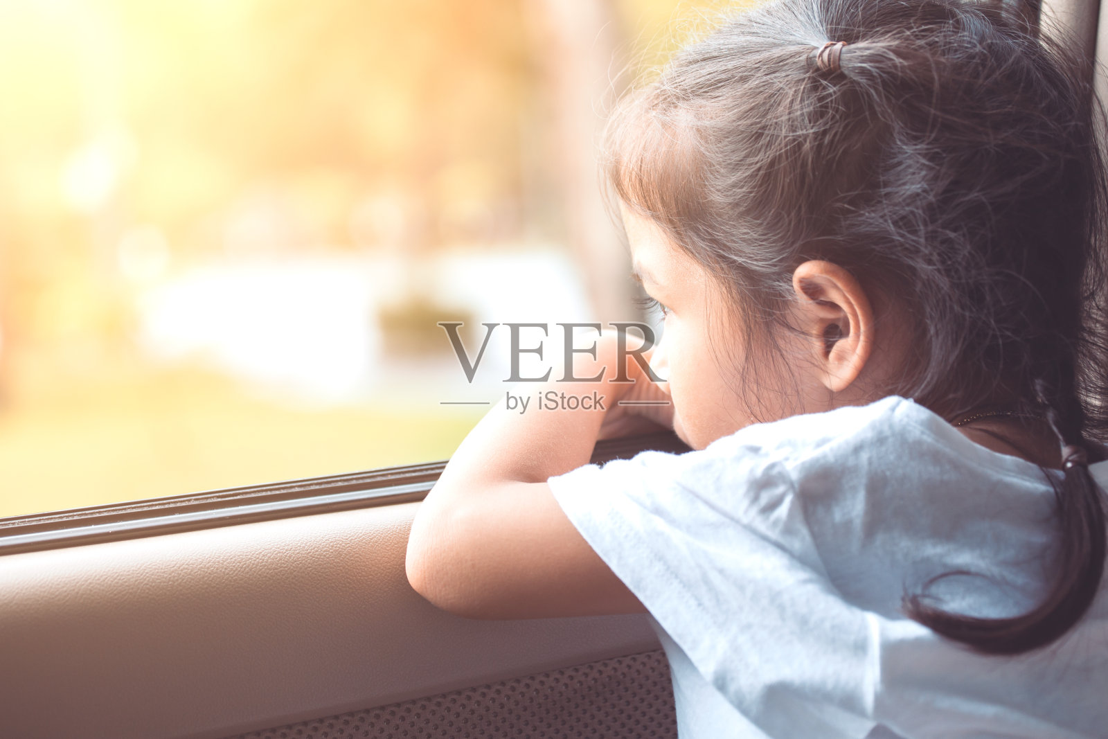 可爱的亚洲小女孩坐在车里，看着窗外照片摄影图片
