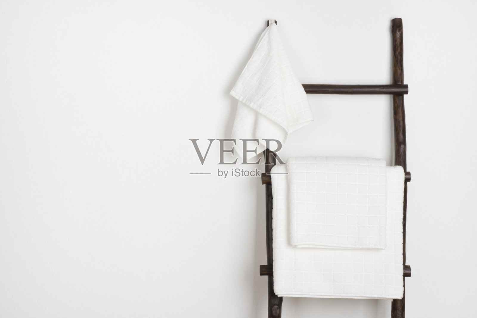 水疗浴巾挂在老式的木制梯上，孤立在白色上照片摄影图片