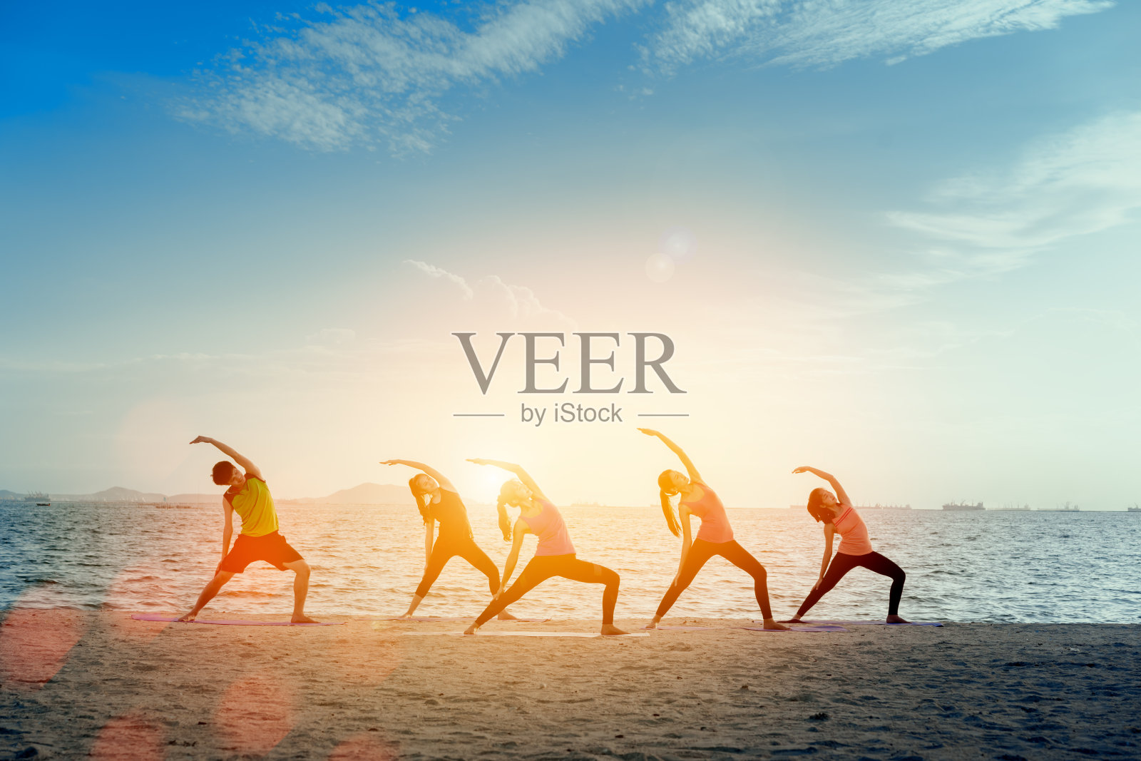 青年组男女瑜伽练习在垫子上放松在课堂运动与姿势健身运动为健康在海滩和海滨现代城市在日出放松假期在夏季假期时间。照片摄影图片