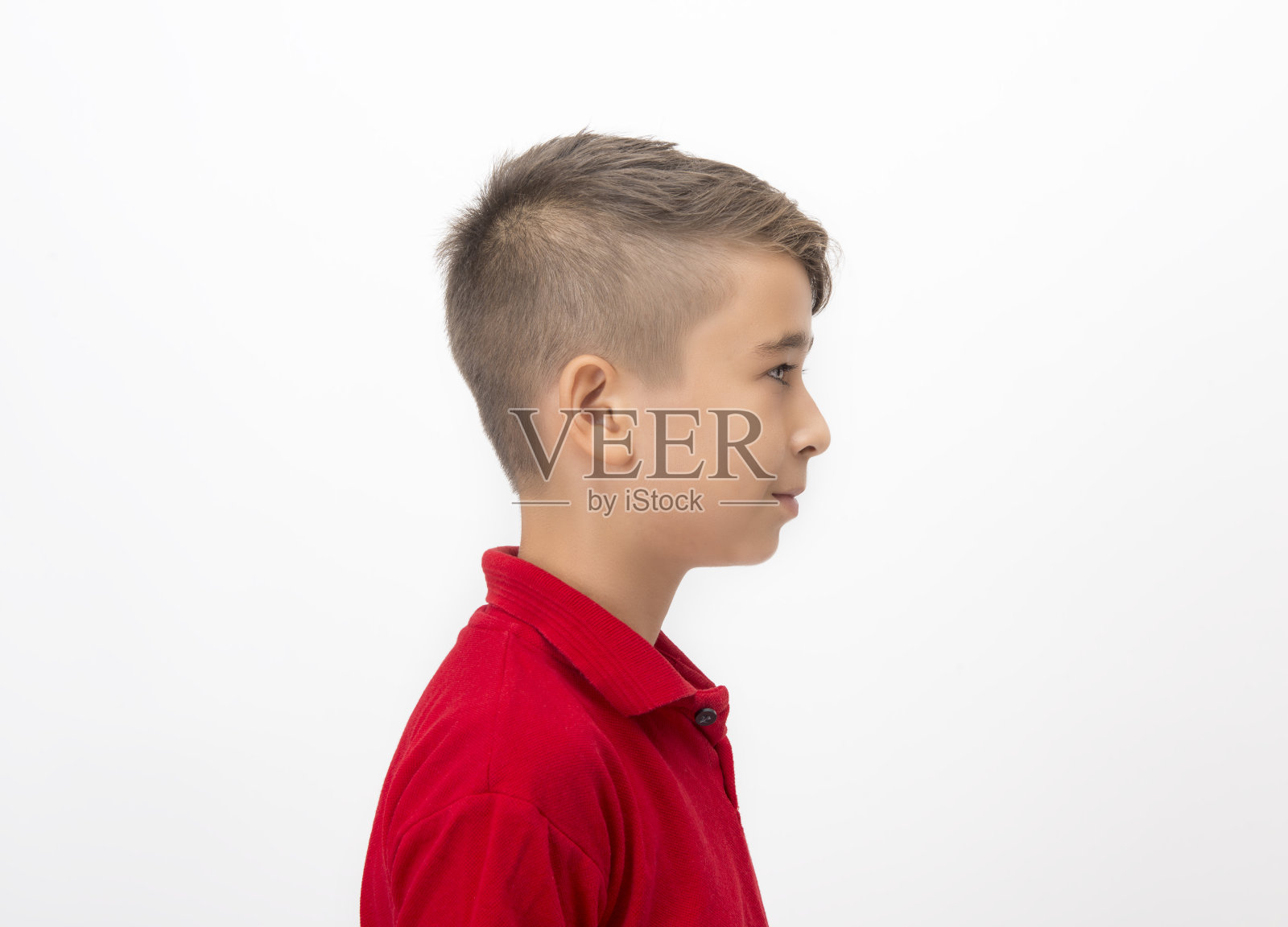 小男孩的侧面视图，站在白色的背景看走开与空白的面部表情照片摄影图片